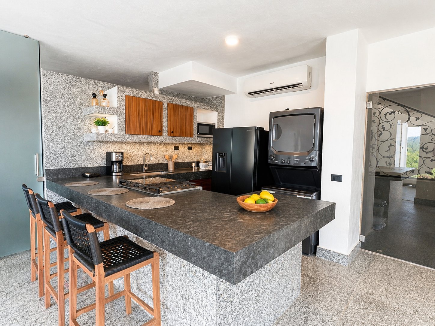 Cocina con barra de granito, gabinetes de madera y lavadora y secadora apiladas