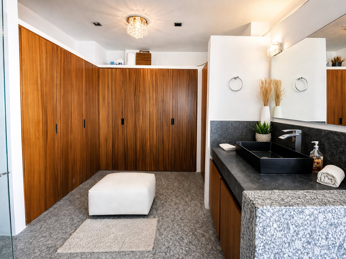 Baño con clósets de madera y lavabo sobre cubierta de granito