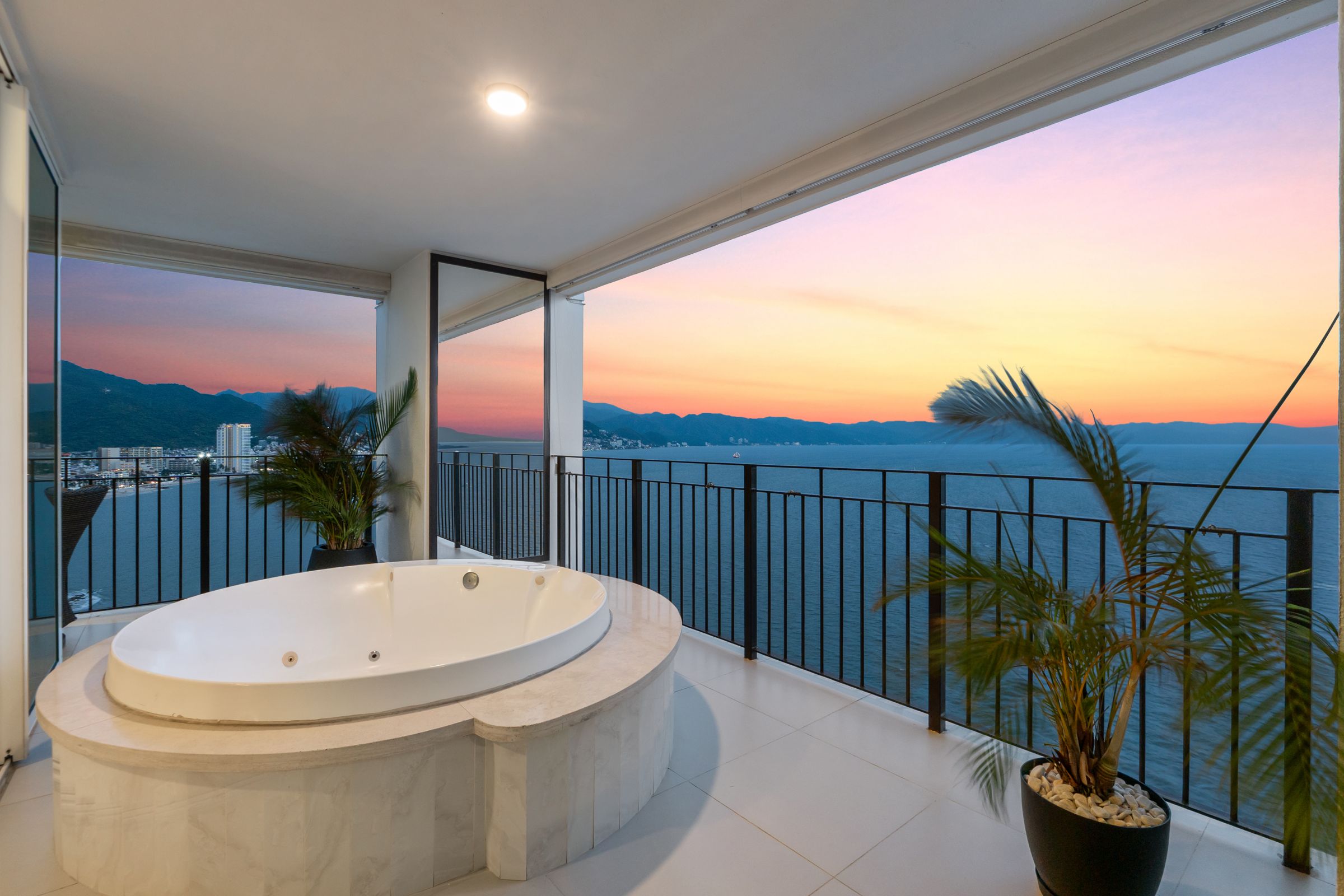 Terrace jacuzzi of Corner Residence 2104 at sunset, with Banderas Bay and the Puerto Vallarta coastline beyond