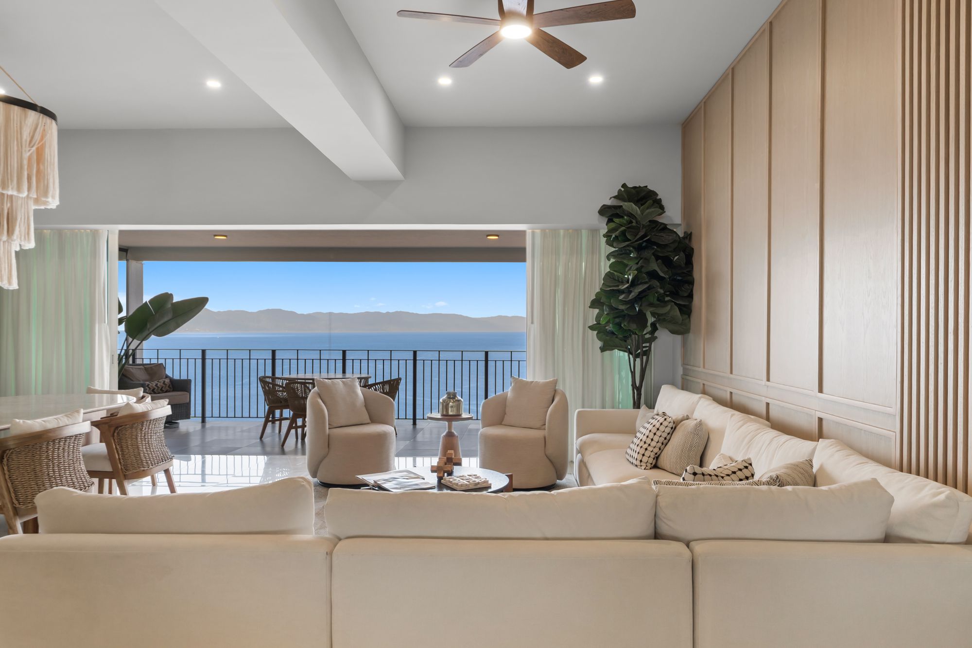 Living room with a sectional sofa and floor-to-ceiling glass doors open to the bay
