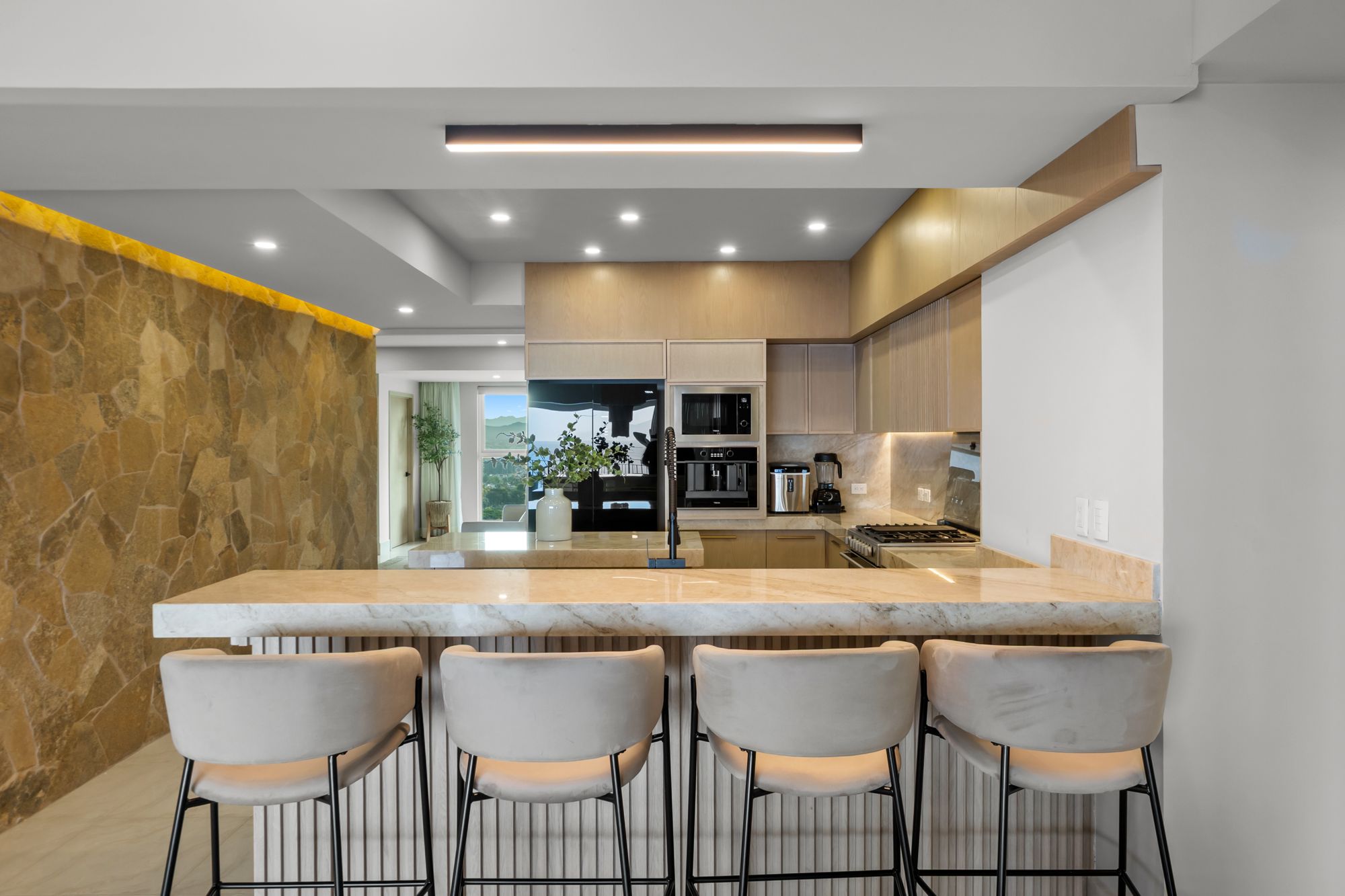 Kitchen with a quartzite breakfast bar, stone feature wall and built-in appliances