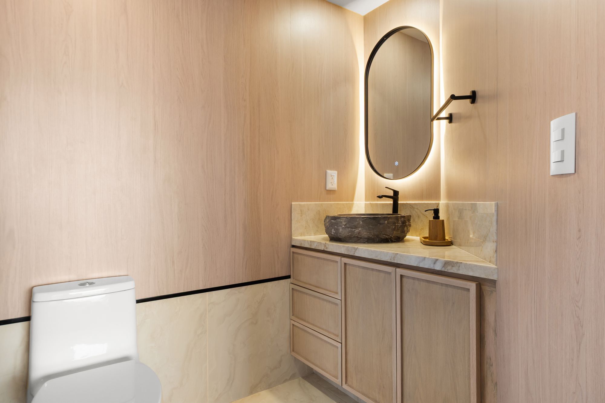 Bathroom with an oak vanity and a backlit oval mirror