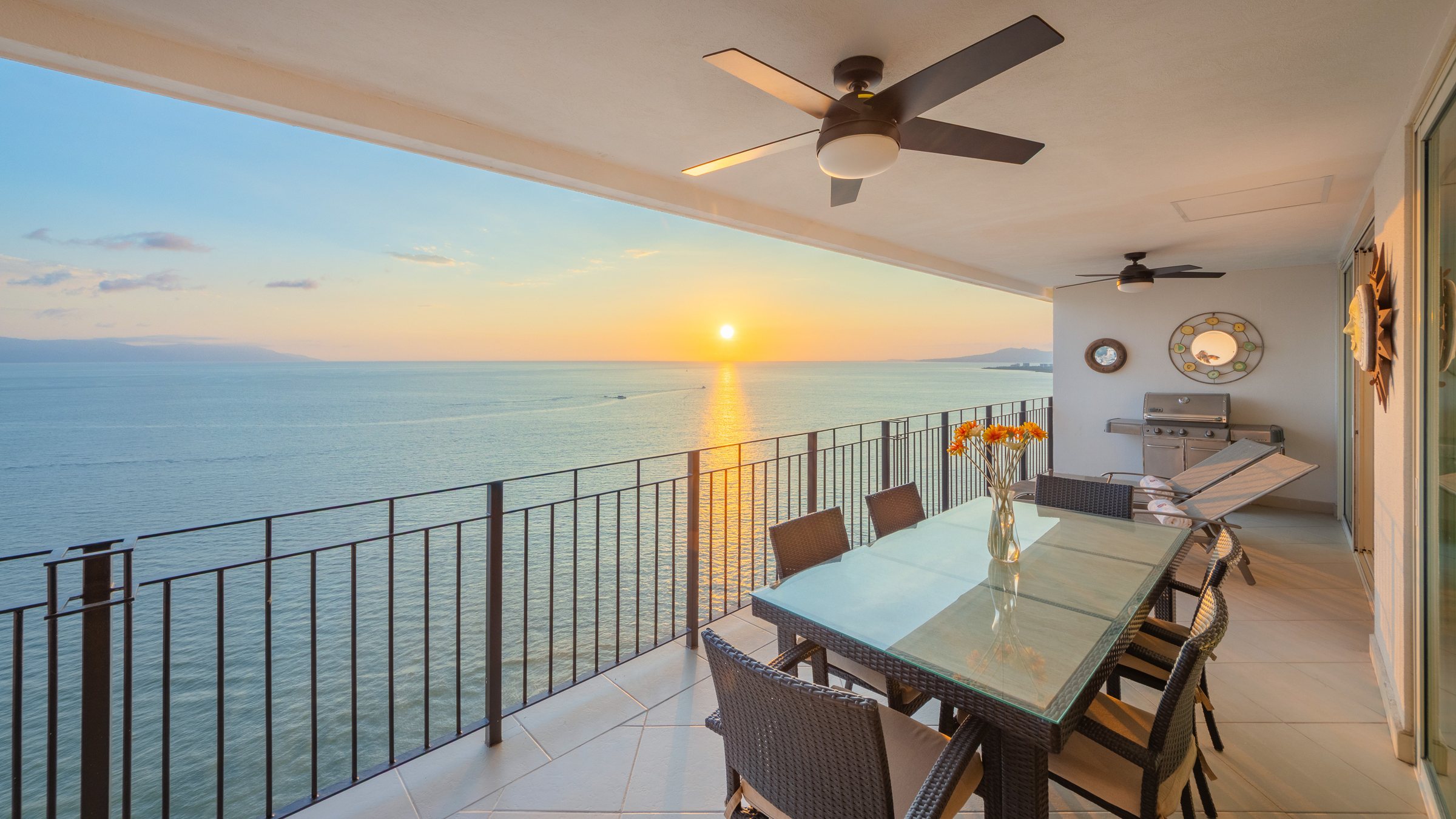 Covered ocean terrace of Penthouse PH1-02 at sunset, with outdoor dining and Banderas Bay