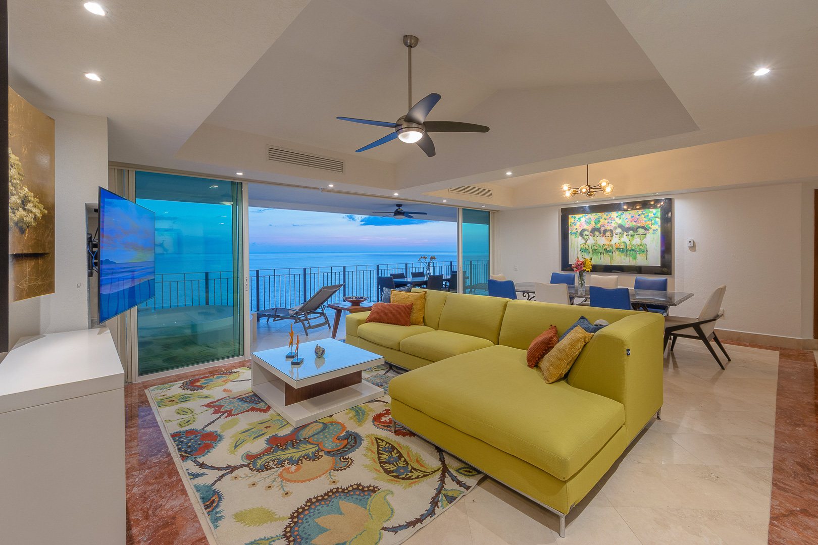 Great room at dusk, open to the terrace and the bay