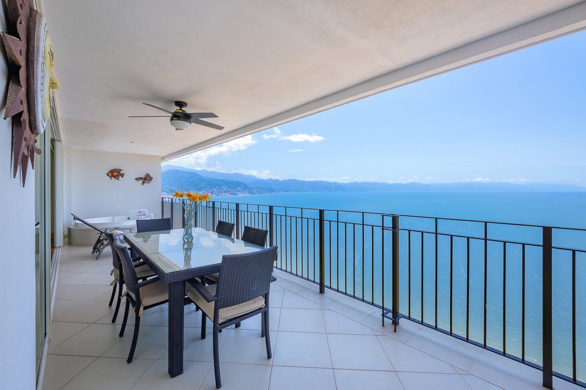 Terraza techada frente al mar del Penthouse PH1-02 de Grand Venetian, con comedor exterior y vista a la Bahía de Banderas y la Sierra Madre
