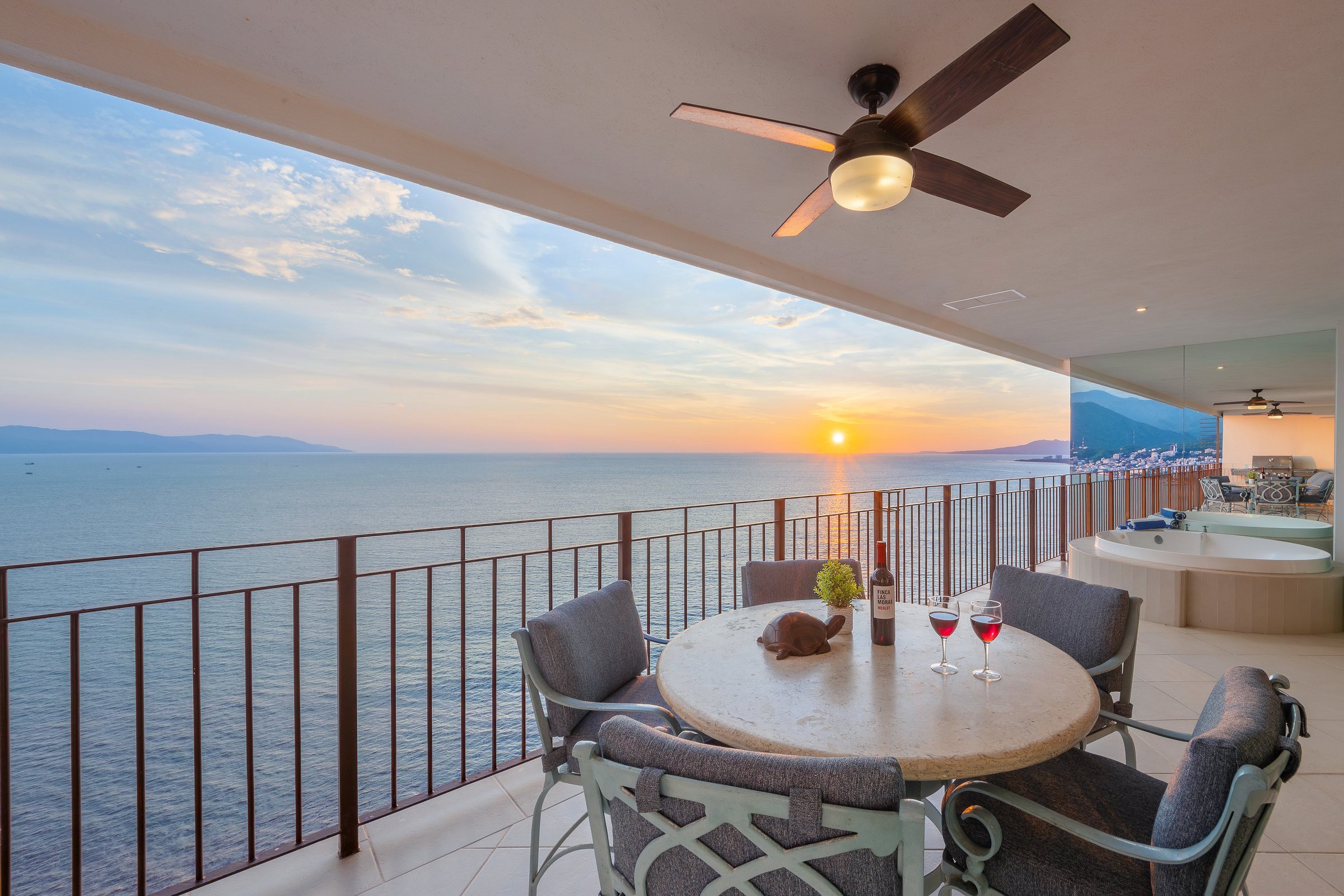 Ocean terrace of Penthouse PH1-03 at sunset, with the dining table, the jacuzzi and Banderas Bay