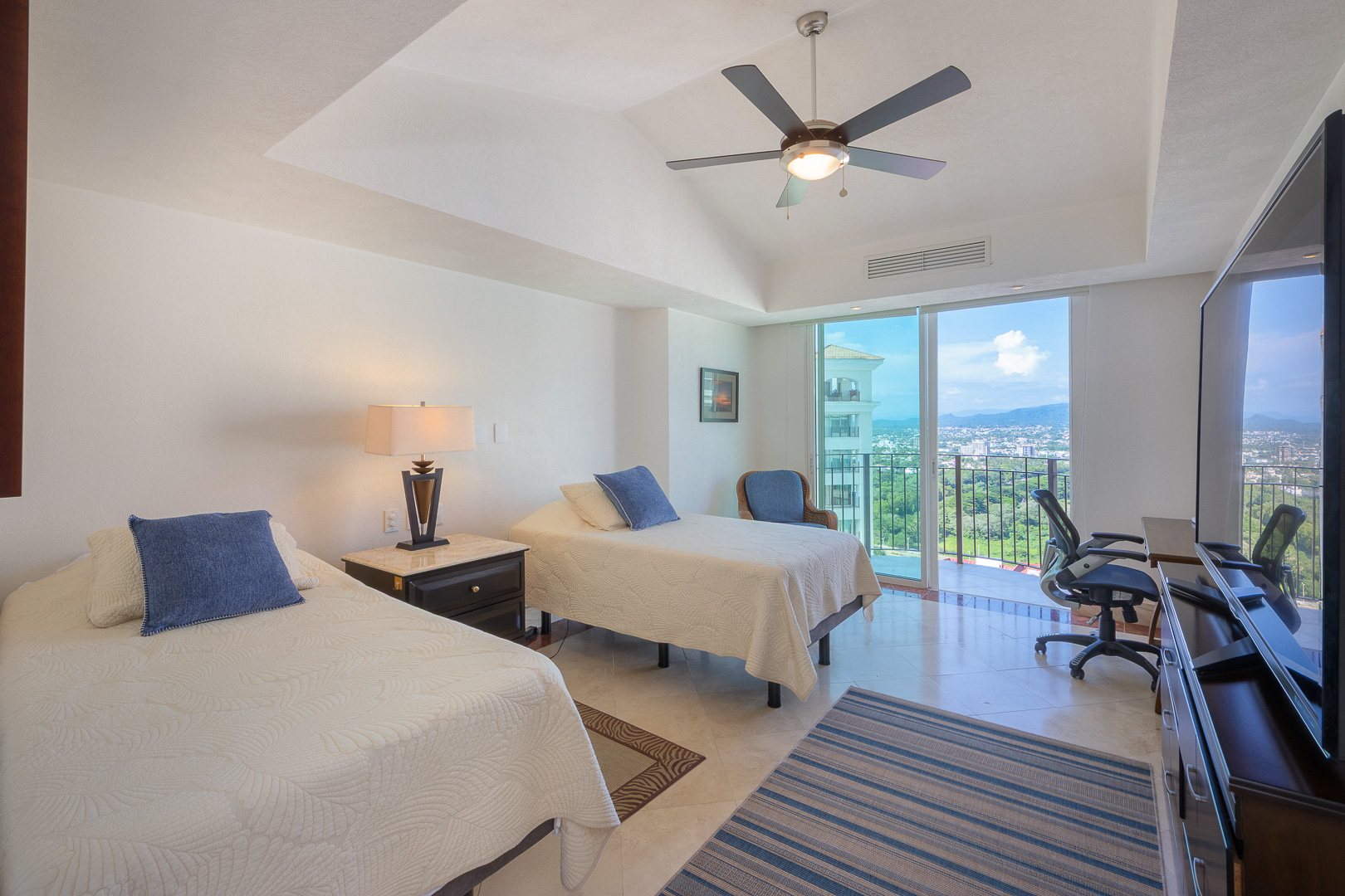 Twin bedroom with a desk and a city view