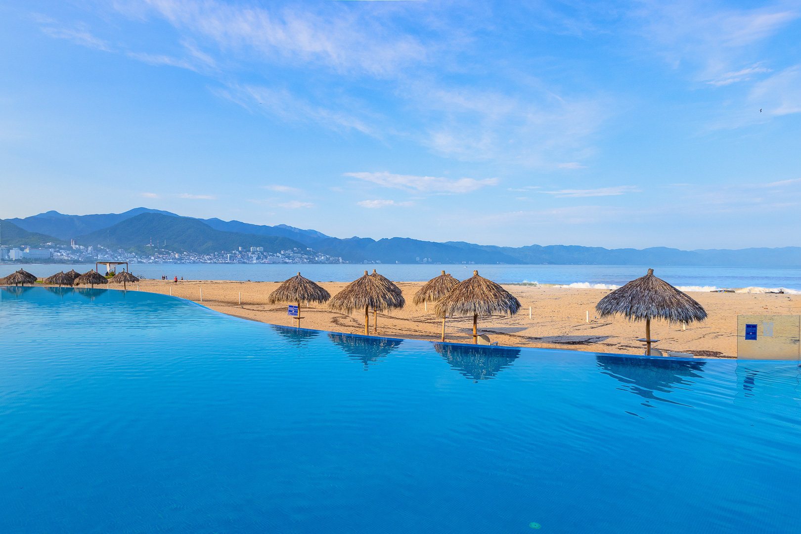 Grand Venetian infinity pool with palapas, the beach and the mountains