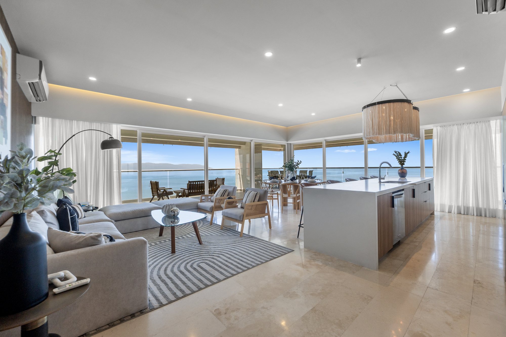 Sala y cocina tras cristales de piso a techo frente a la bahía