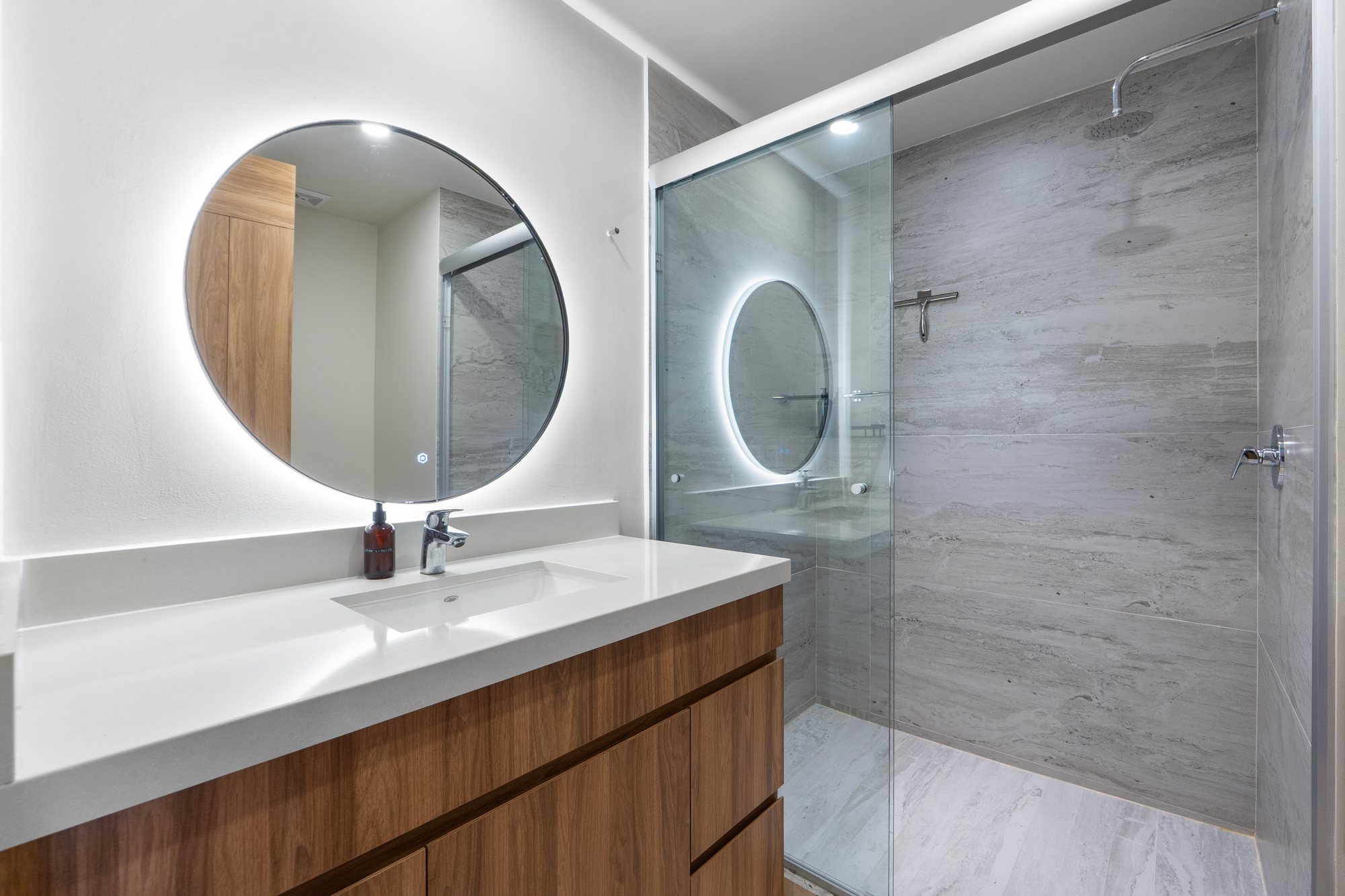 Baño con recubrimiento tipo piedra y regadera de cristal