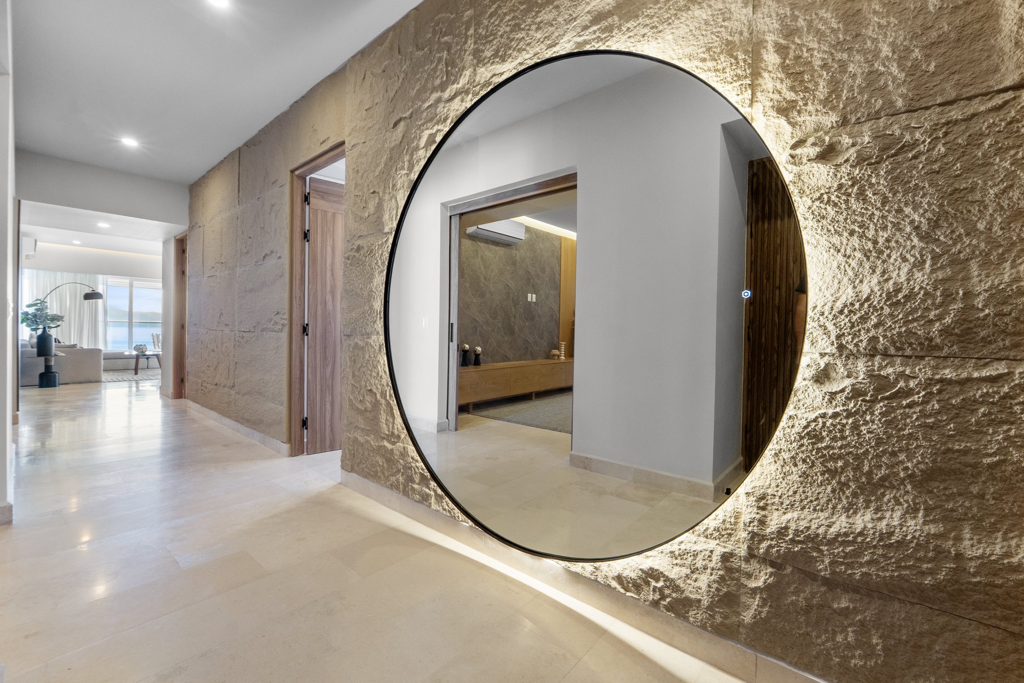 Vestíbulo con muro de piedra labrada y espejo redondo iluminado
