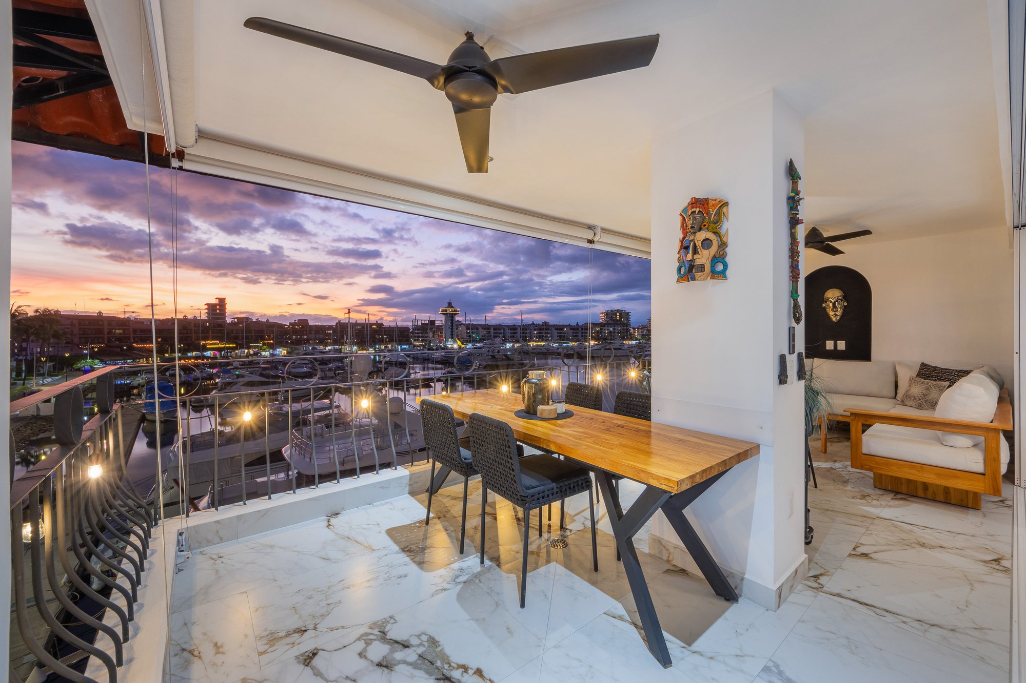 Terraza con comedor y sala, con la marina iluminada al fondo