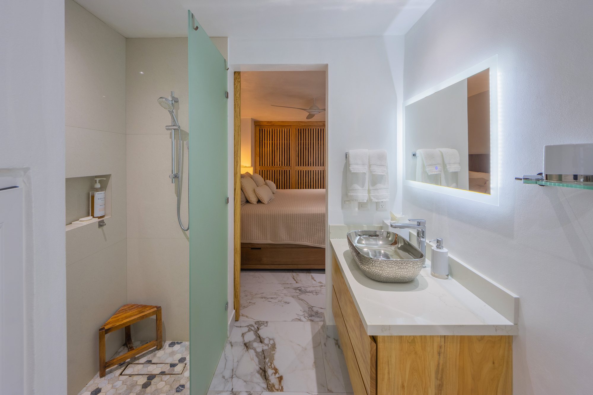 Baño con regadera de cristal, abierto a una recámara