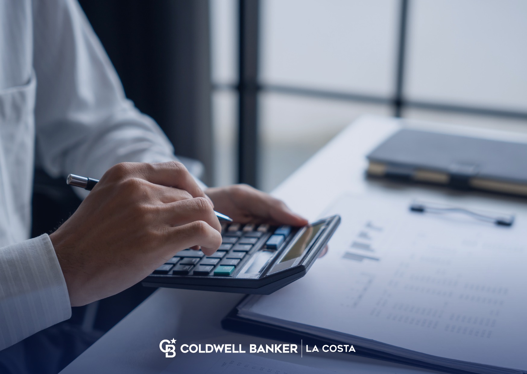 Mano usando una calculadora junto a documentos financieros sobre un escritorio, como s&iacute;mbolo de la planeaci&oacute;n hipotecaria para comprar una propiedad en M&eacute;xico