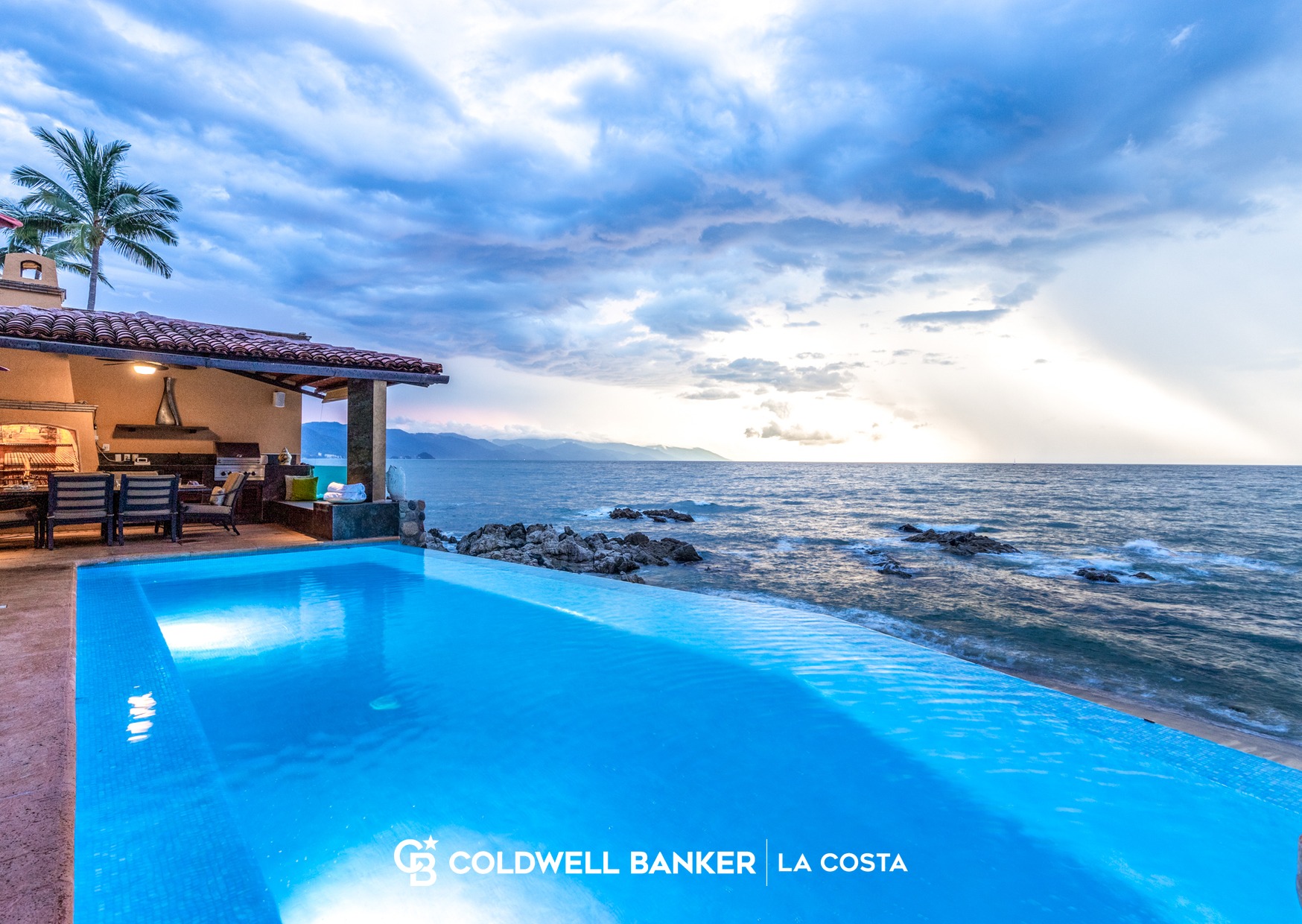 Alberca infinita al atardecer con vista al oc&eacute;ano junto a una terraza techada en una renta vacacional de Bah&iacute;a de Banderas