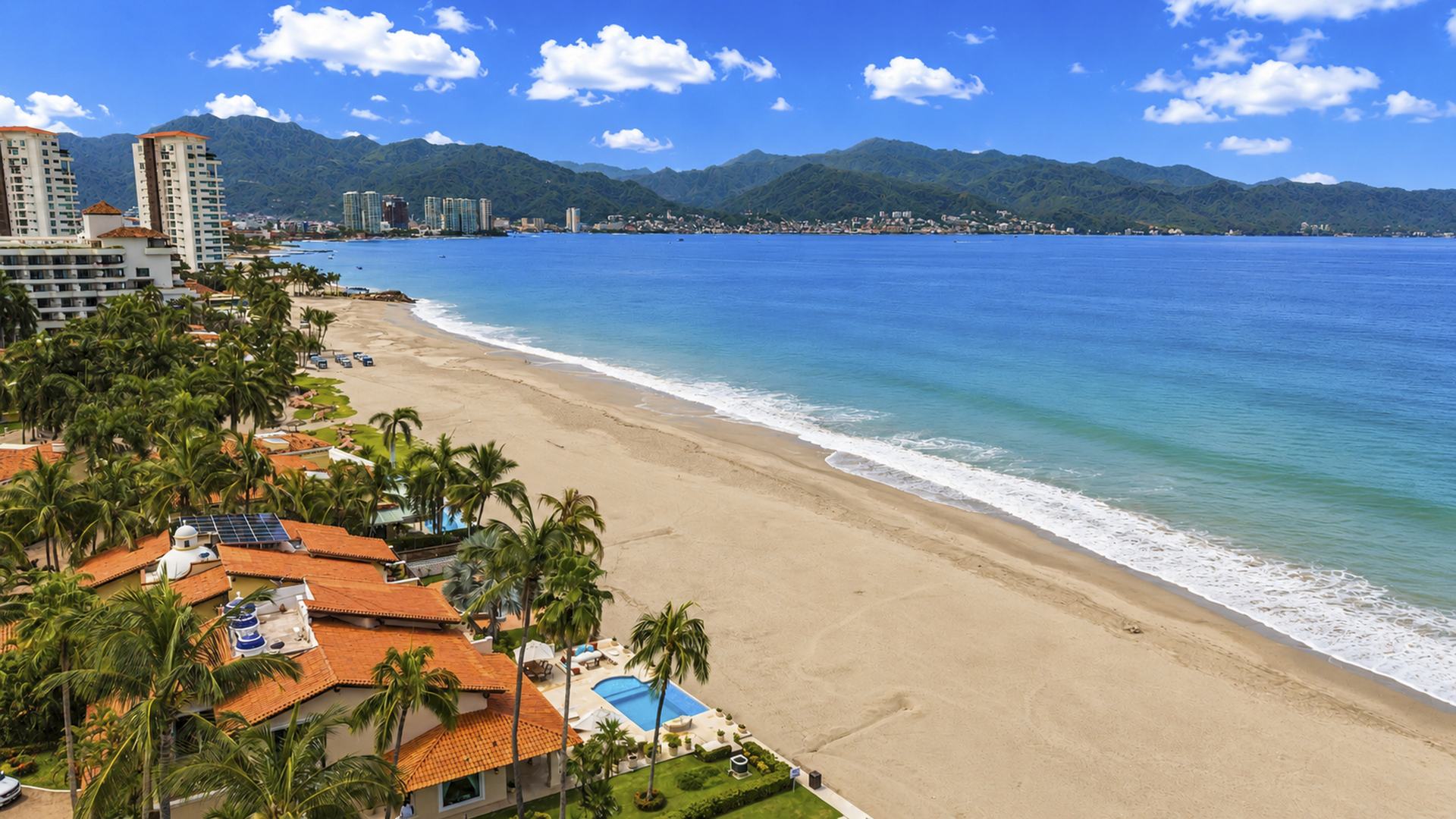 Aerial view of the Condominios Caracoles villas on the sand, with the beach, Banderas Bay and Puerto Vallarta behind