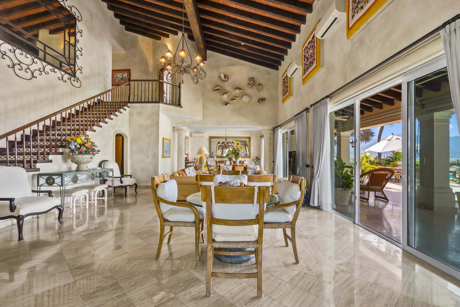 Living and dining area with marble floors and the staircase to the upper level
