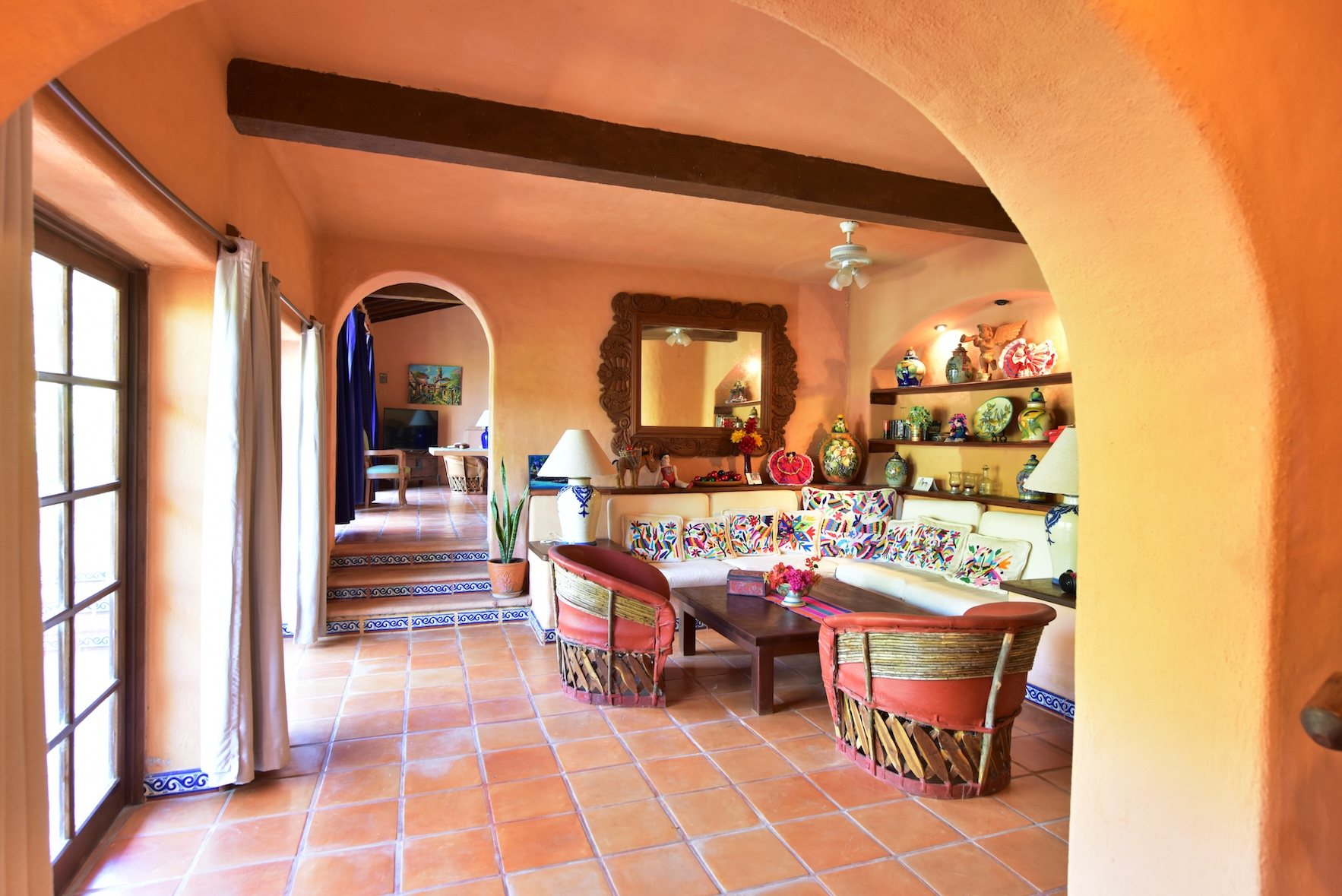 Sala bajo arcos, con sillones de equipal y repisas de talavera