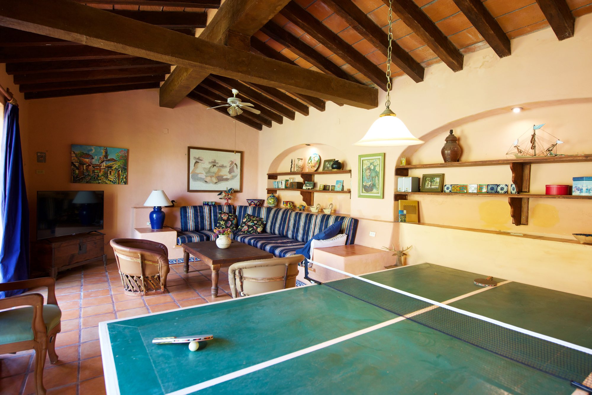 Sala familiar con techo de vigas, sofá y mesa de ping-pong