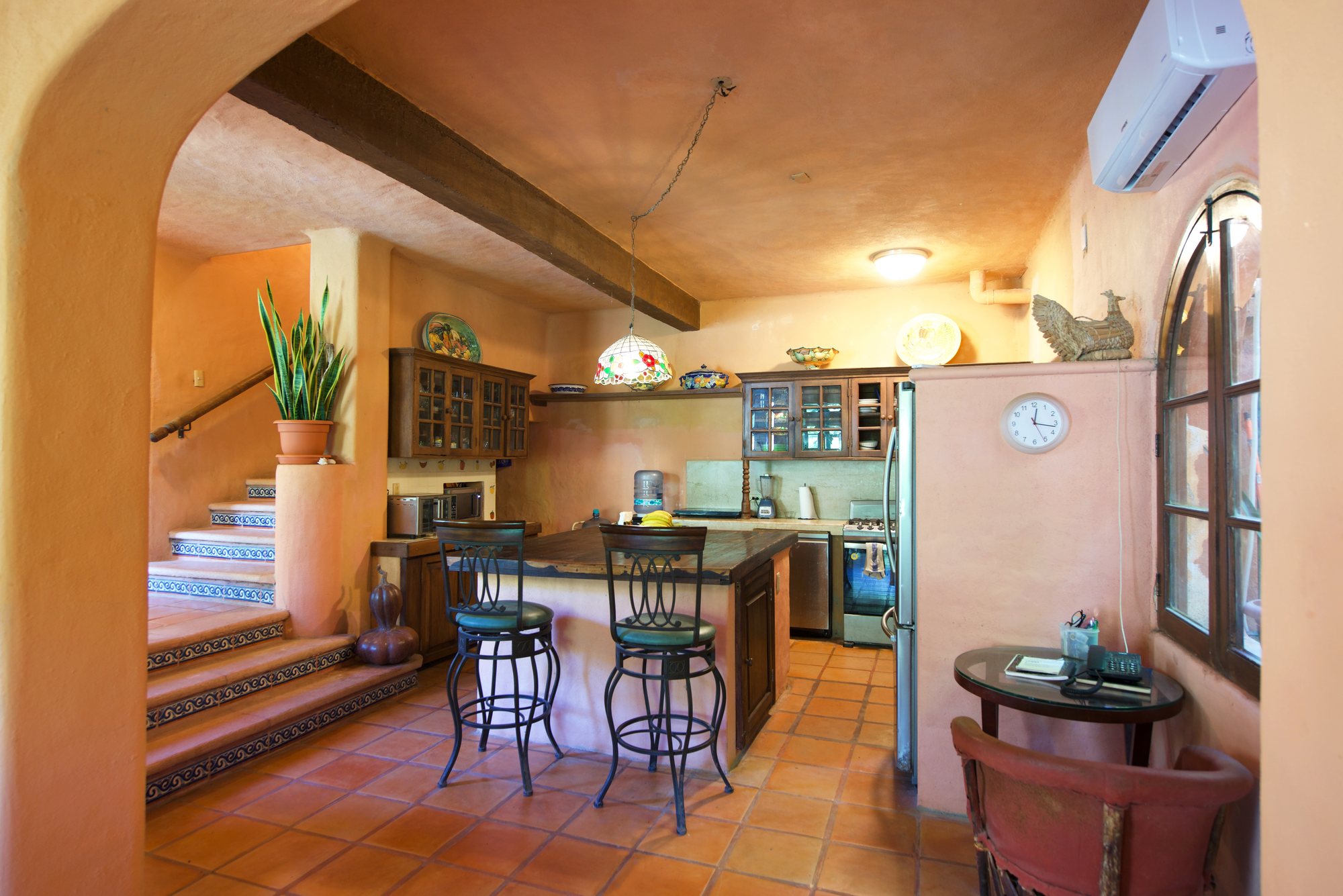 Cocina con isla, barra de desayuno y escalera al fondo