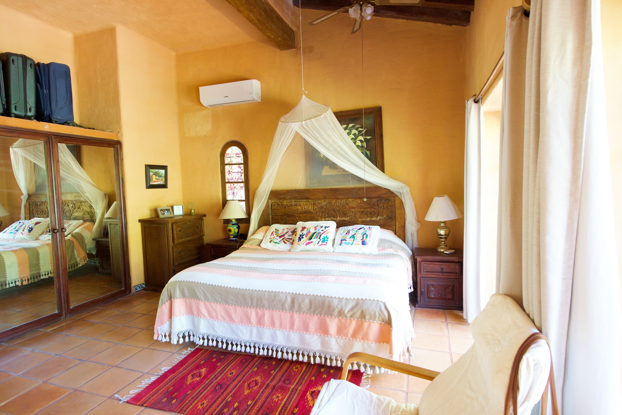 Recámara con cama de madera tallada y aire acondicionado minisplit