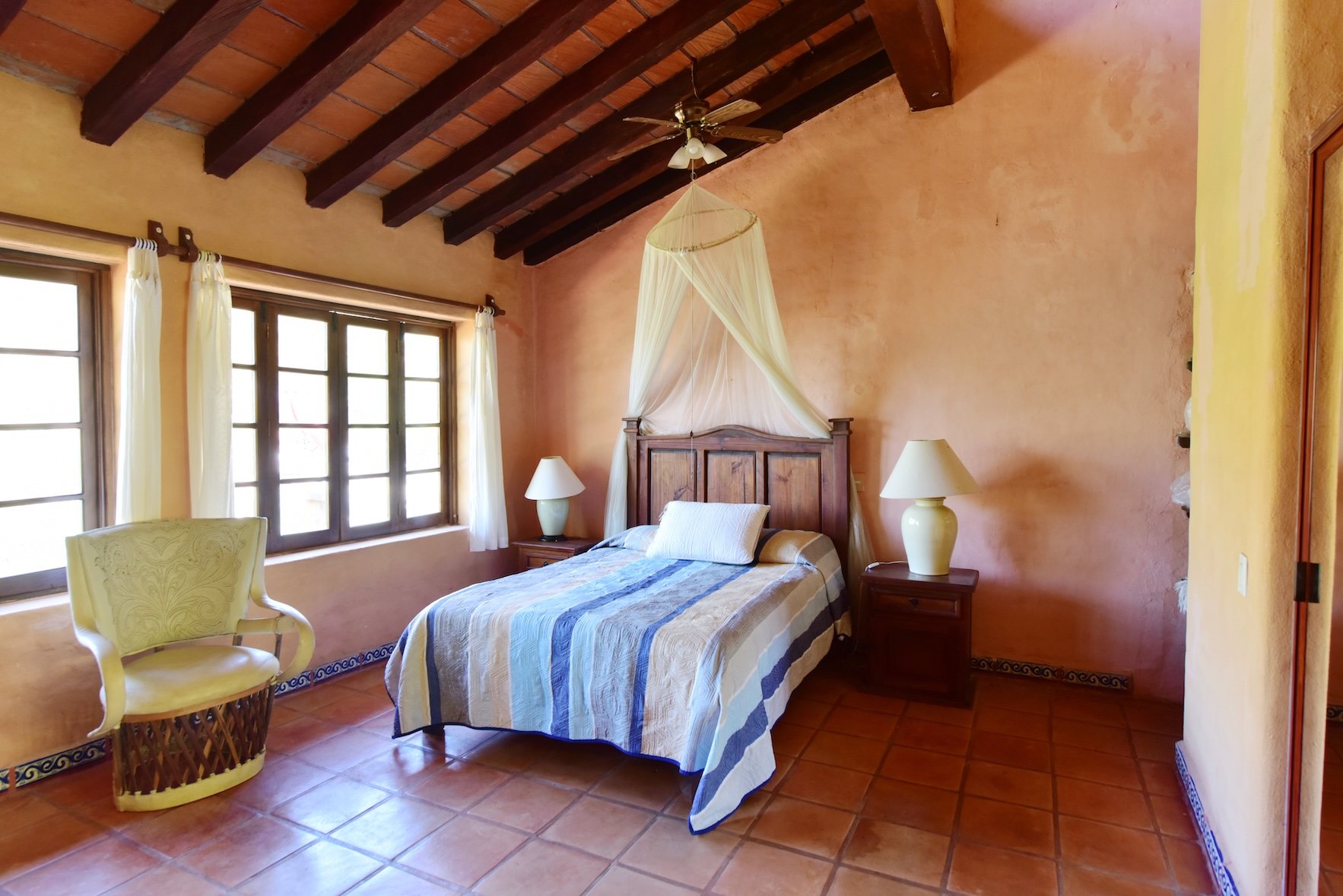 Recámara con ventanas y sillón de equipal