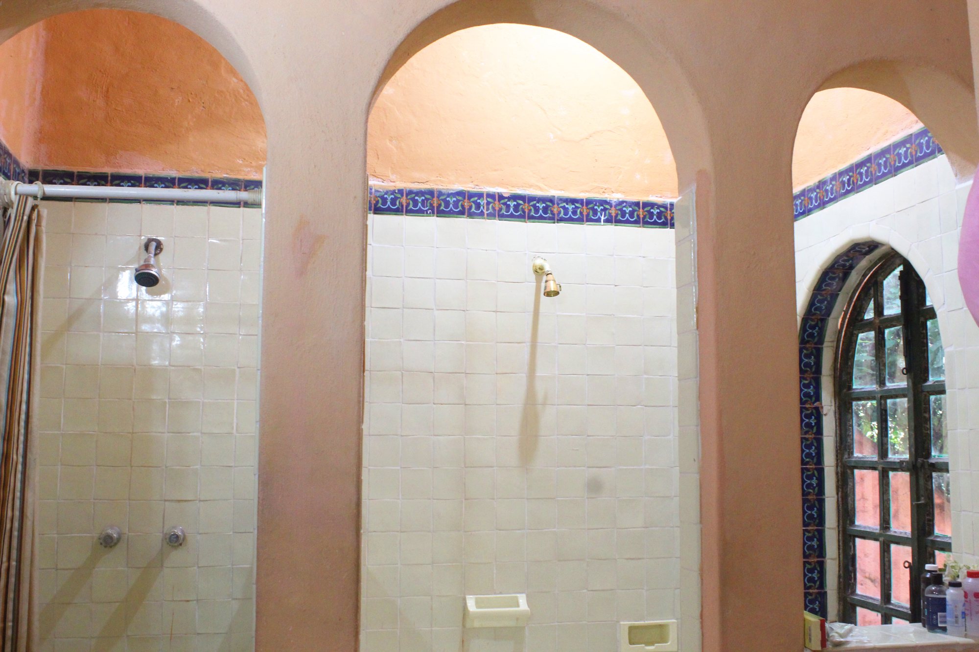 Baño con regaderas bajo arcos y ventana al jardín