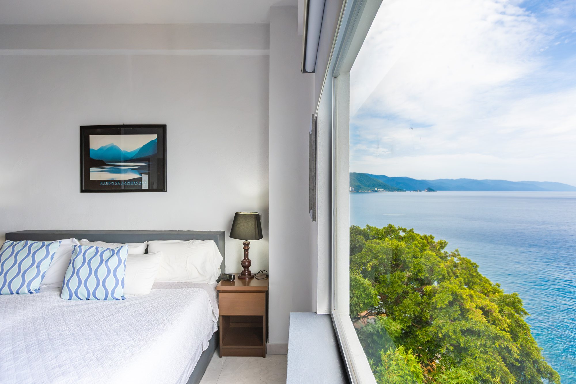 Bedroom with a wall of glass over the coast