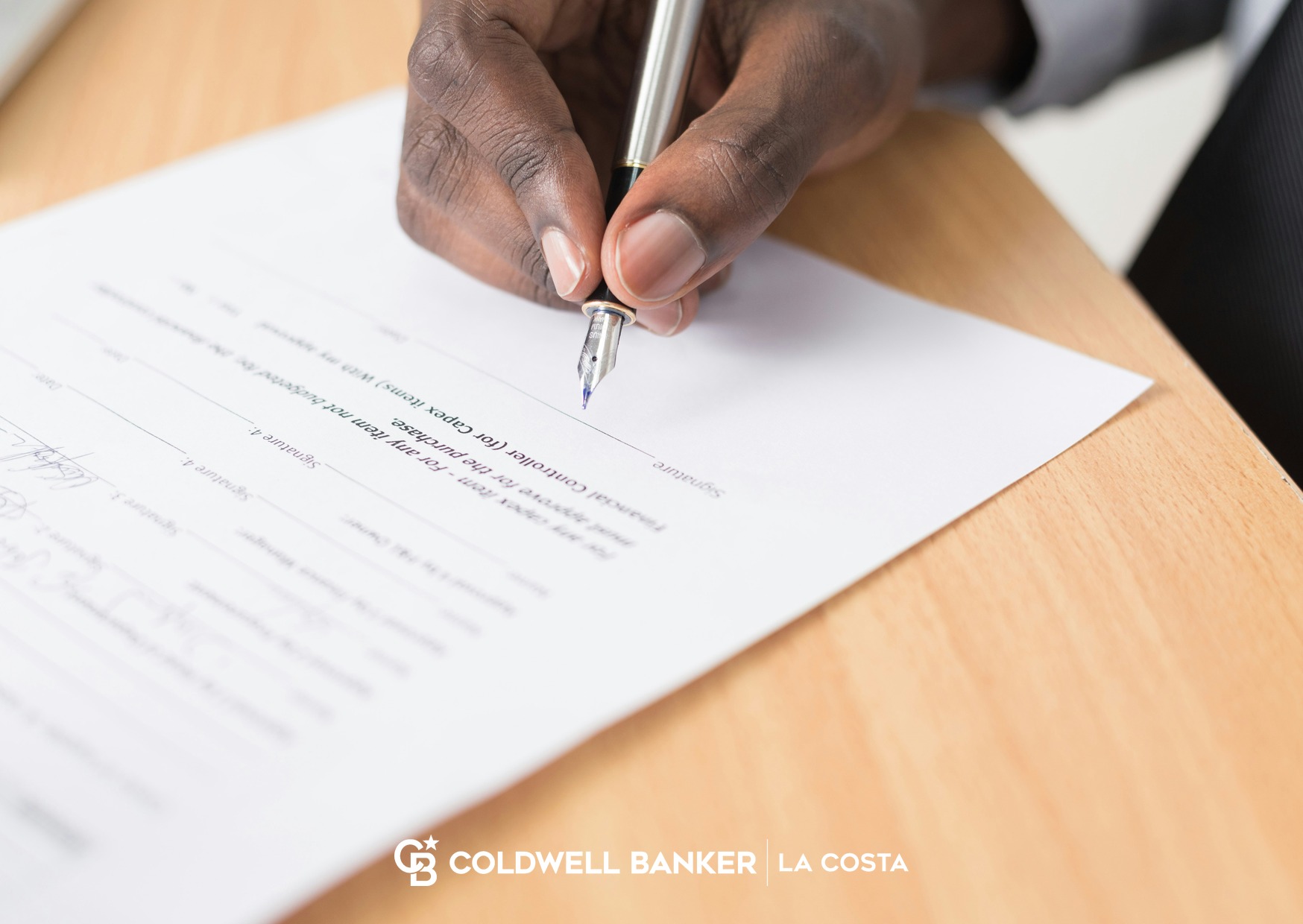 A hand signing a document with a fountain pen, representing a Mexican will for a foreign property owner