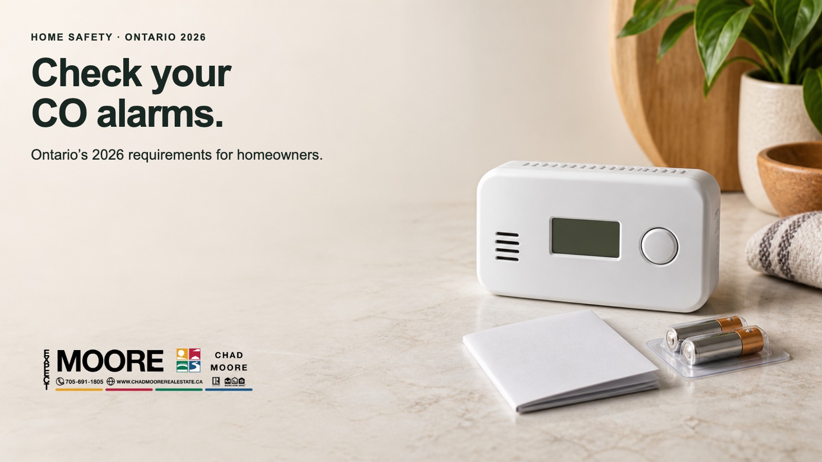 Carbon monoxide alarm on a table beside replacement batteries, with a reminder to check your alarms