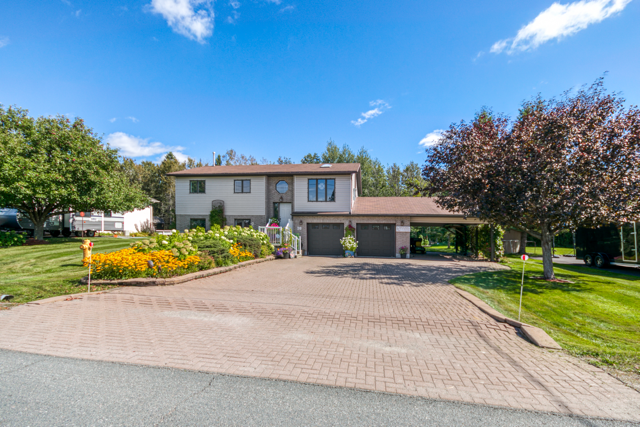 Wide view of the front lawn, home and paved driveway