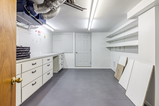 Basement workshop in the main home with half-door access toward the backyard beneath the deck landing