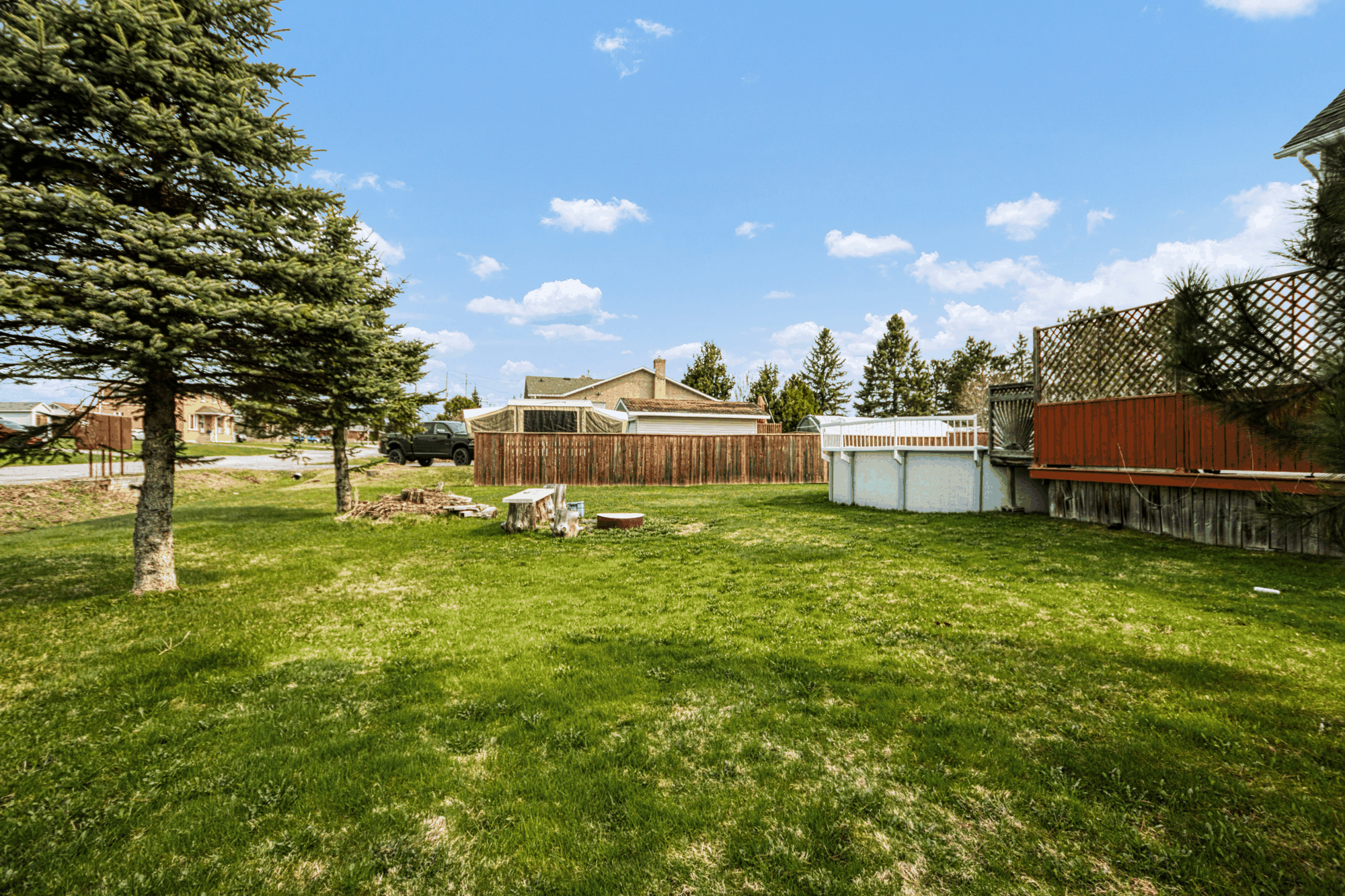 Wide rear yard with mature trees and above-ground pool
