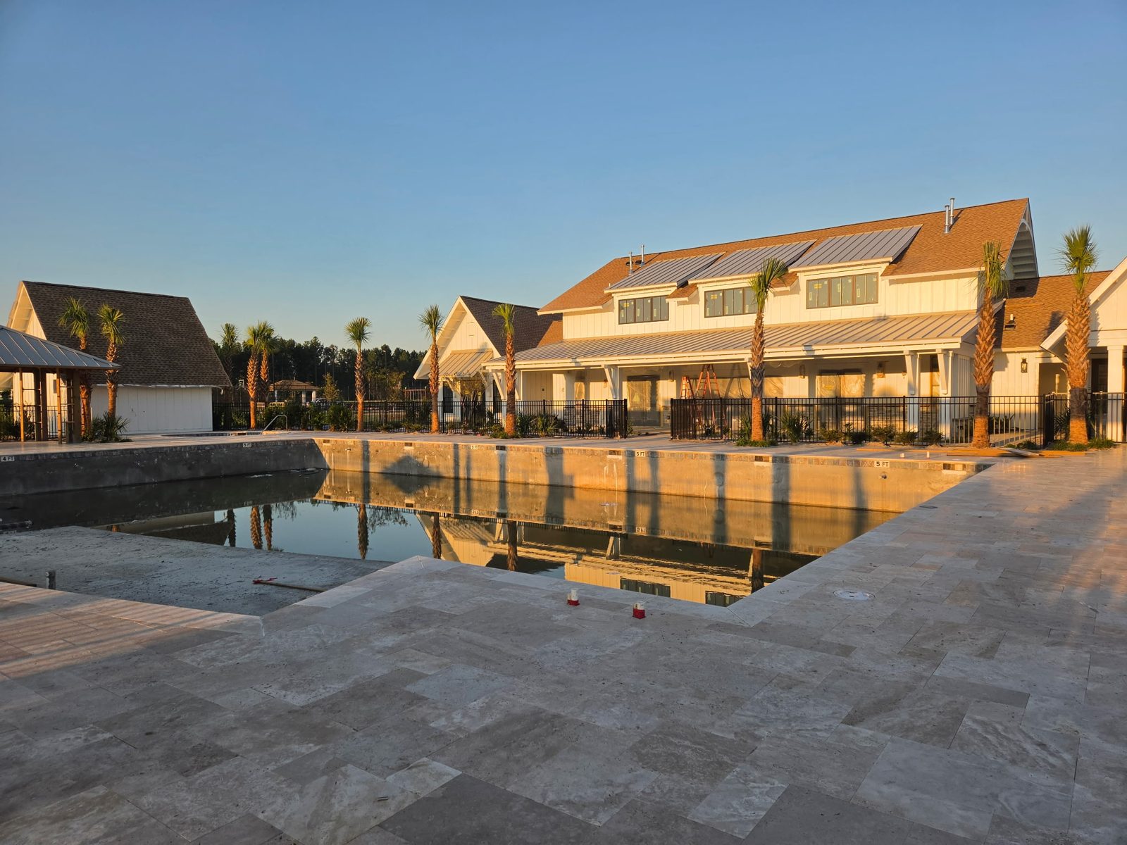 Main pool under construction with travertine deck and clubhouse behind