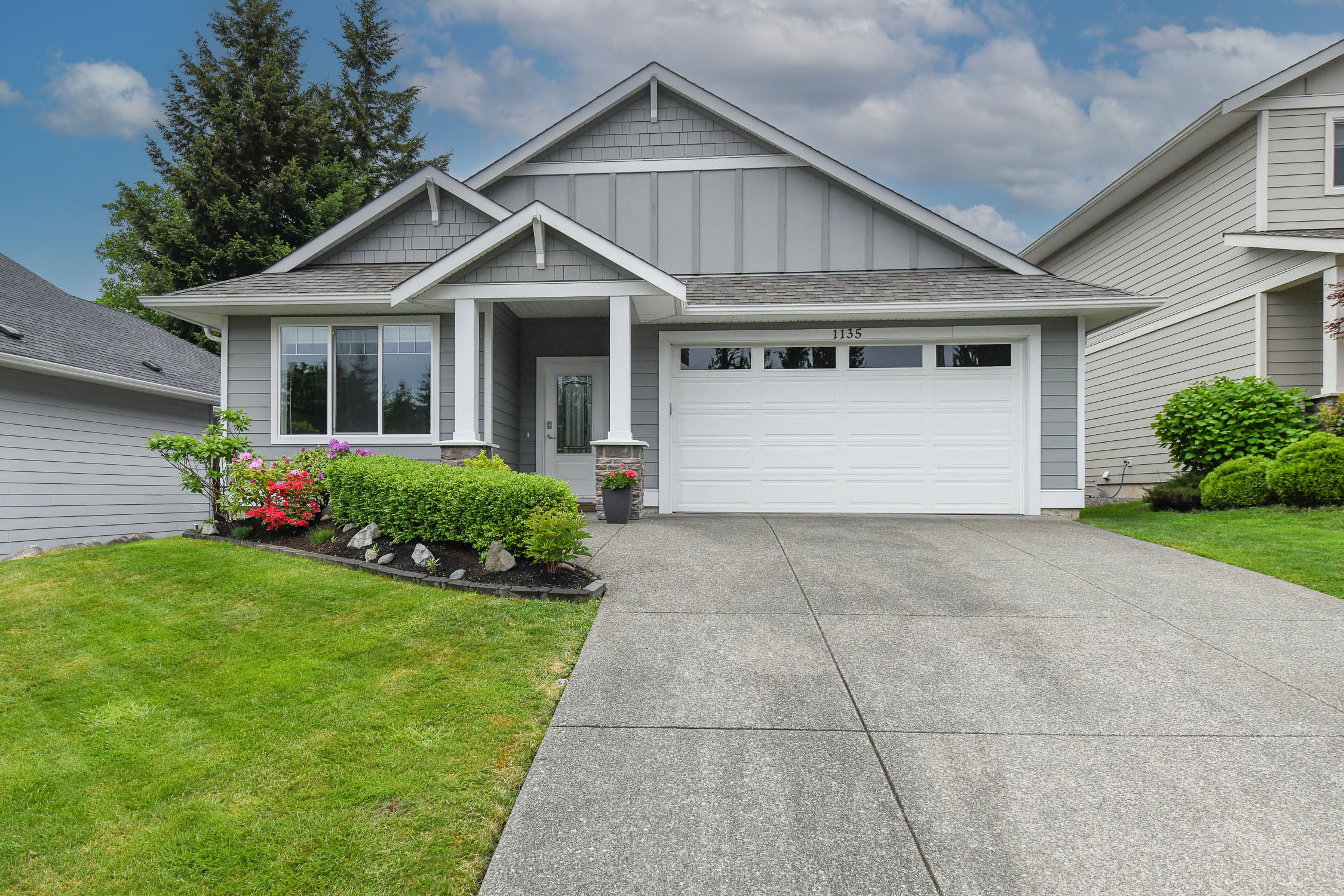 Beautifully maintained rancher at 1135 Crown Isle Blvd in Courtenay featuring open-concept living, quartz countertops, covered patio, and a sunny south-facing backyard with mature landscaping and roses.