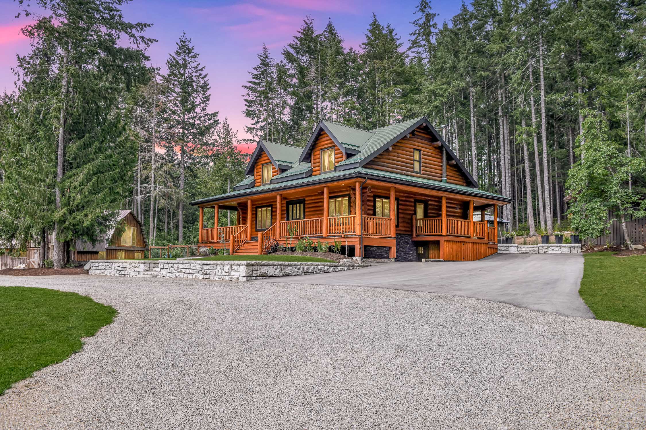 Luxury 3-bedroom custom log home at 1258 Barr Dr in Merville featuring wrap-around decks, a gourmet chef's kitchen, beautifully landscaped grounds, a fenced garden, and a three-stall barn near Williams Beach and equestrian trails.