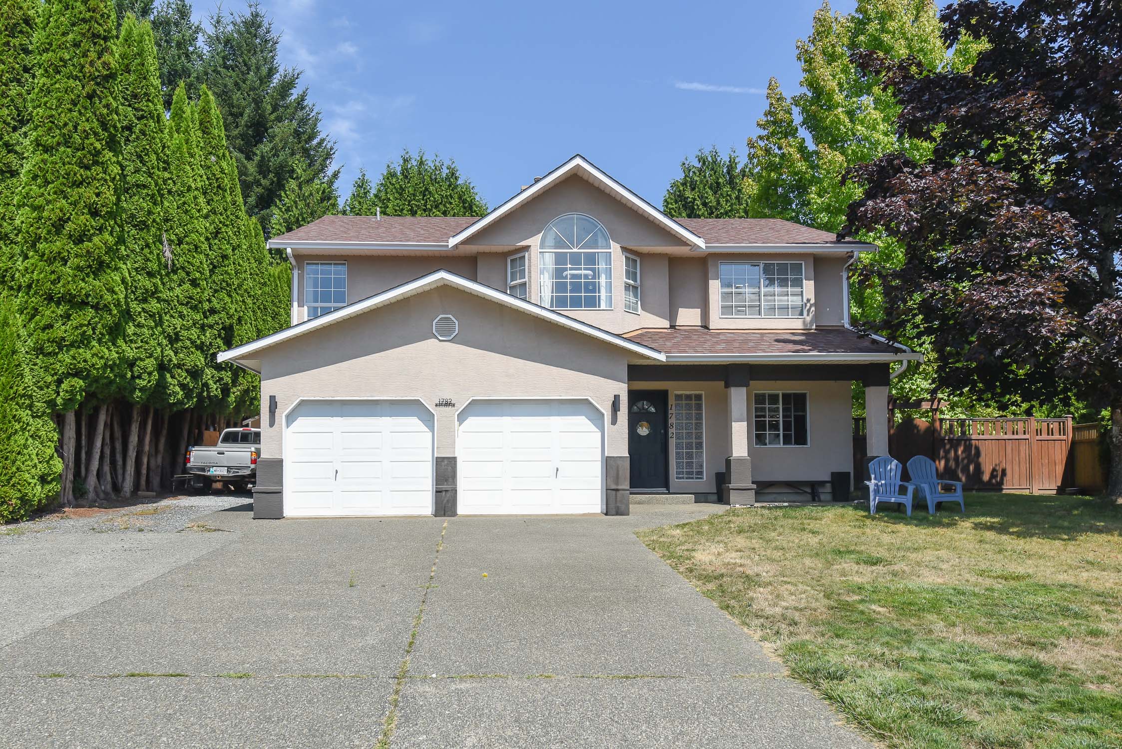 Front exterior view of 1782 Mallard Dr in Courtenay, BC, showcasing a well-maintained East Courtenay family home with attractive landscaping, private fenced yard, and spacious residential setting&mdash;highlighting desirable Comox Valley real estate with 5 bedrooms, an in-law suite, mountain views, and convenient access to schools, parks, shopping, and CFB Comox.