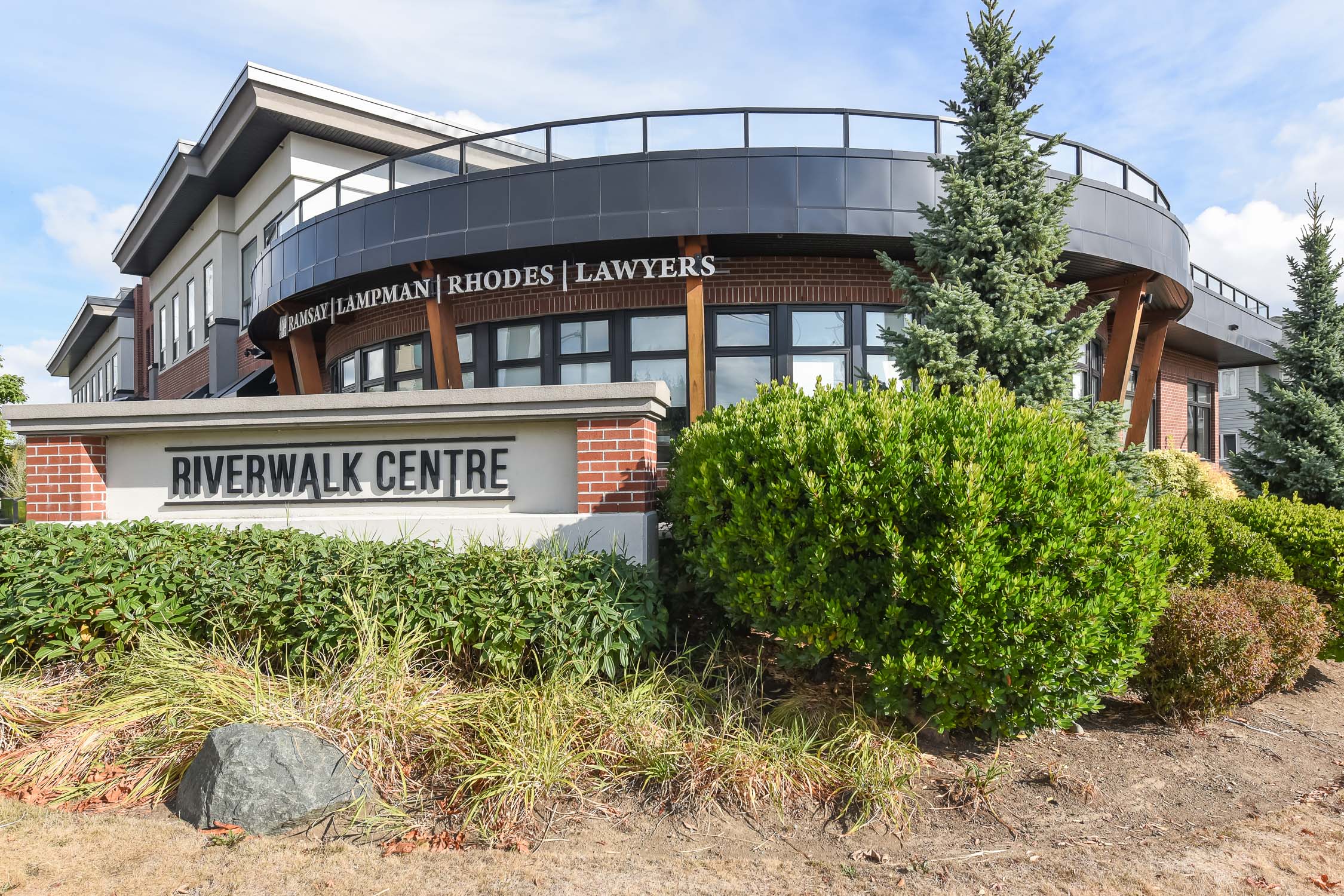 Contemporary 1-bedroom loft-style condo at 308-1978 Cliffe Ave in Courtenay, featuring 15-foot ceilings, oversized windows, modern finishes, and southeast-facing views toward the Puntledge River and Airpark.