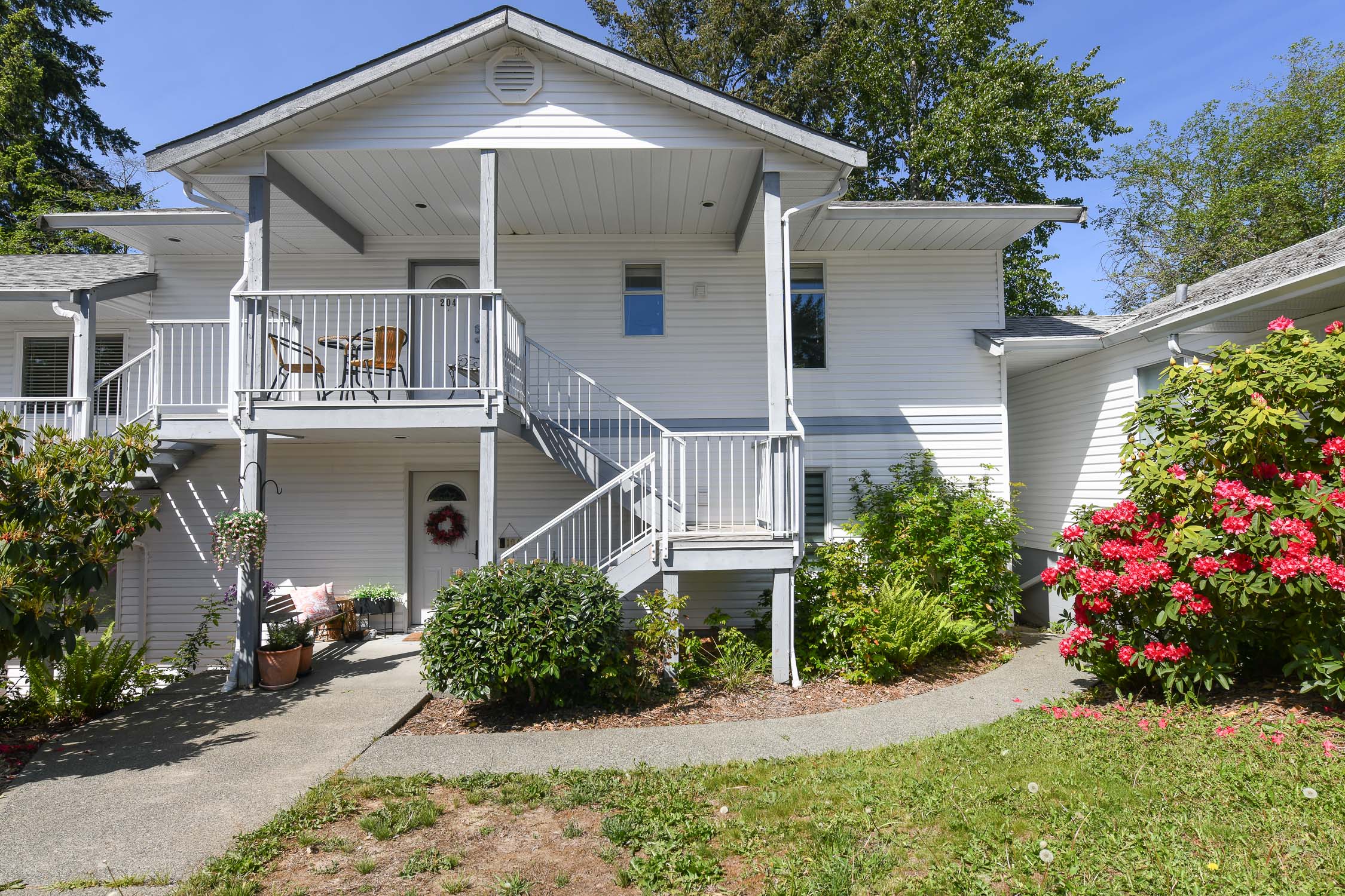 Bright top-floor condo at #204 220 Back Rd in Courtenay featuring south-facing exposure, skylight, private covered balcony, and peaceful tree and garden views in a convenient East Courtenay location.
