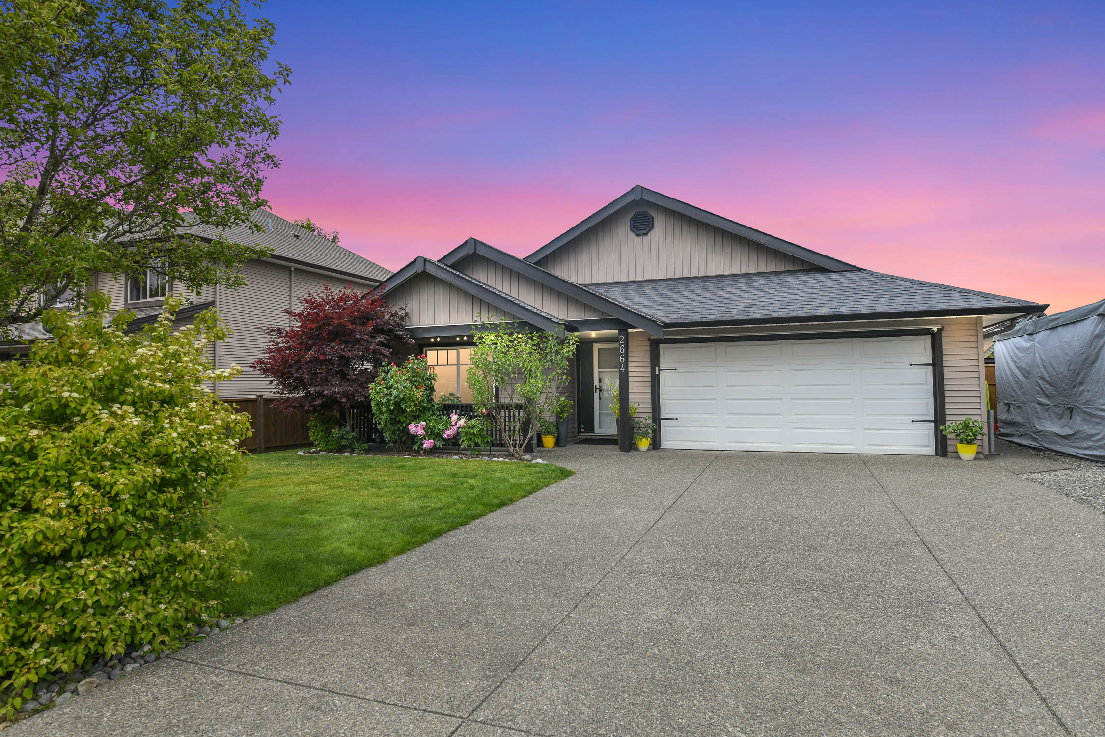 Front view of the rancher at 2664 Rydall Ave in Cumberland, featuring landscaped yard, double garage, and driveway with space for RV or boat parking.