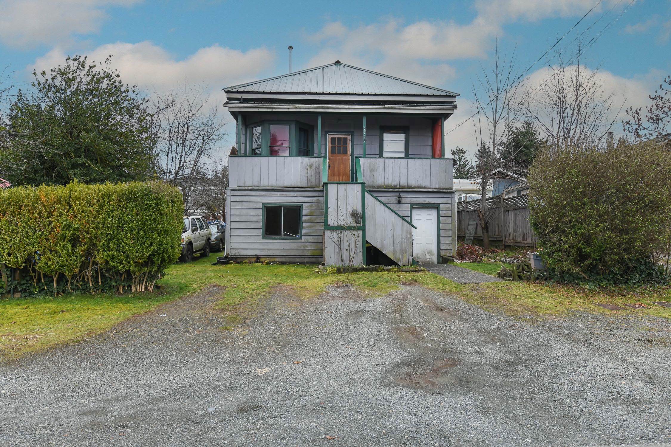 Front exterior view of 2745 Derwent Ave in Cumberland, BC, showcasing a historic 1894 heritage home with classic character, mature landscaping, and a fully fenced lot&mdash;highlighting one of Cumberland&rsquo;s original residences in a walkable village location near trails, shops, and Comox Lake on Vancouver Island.