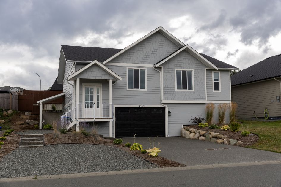 Exterior view of a modern 2021-built Step Code 5 home in The Ridge, Courtenay, featuring contemporary architecture, landscaped front yard, double garage, and clean curb appeal&mdash;showcasing energy-efficient design and high-quality construction on Vancouver Island