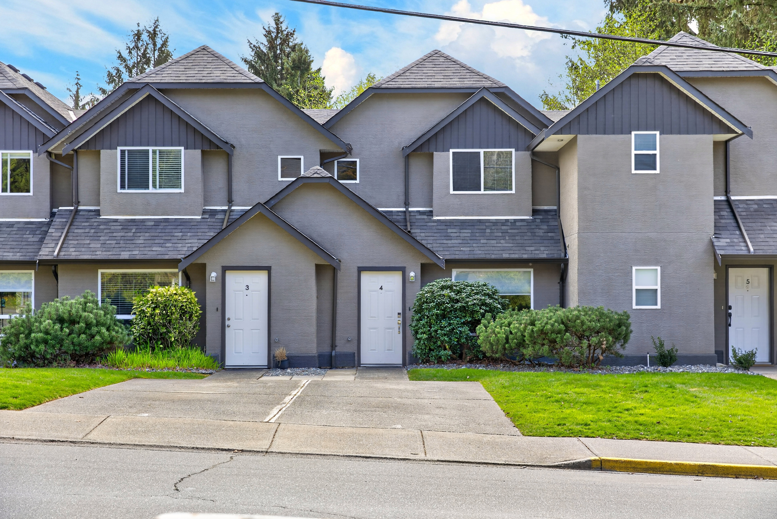 Front exterior of a well-maintained townhome in the Creekside complex, featuring a private driveway and expanded yard space compared to surrounding units. The home is positioned along the outer edge of the development, offering added privacy with a quiet residential feel while still being close to all amenities in Campbell Rive