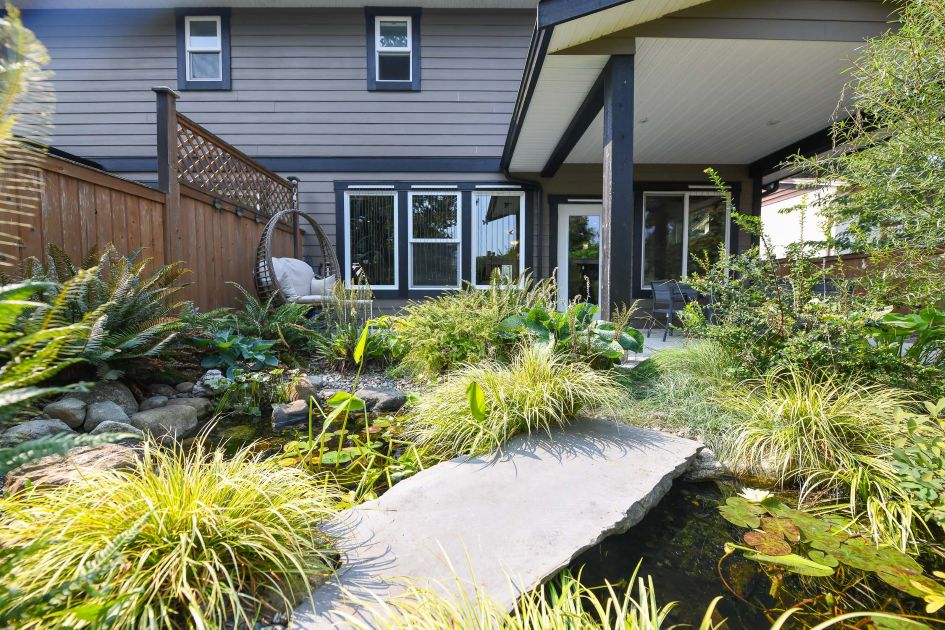 private landscaped backyard at 4684a macintyre ave courtenay bc featuring a mature garden oasis with pergola pond fruit trees and berry bushes