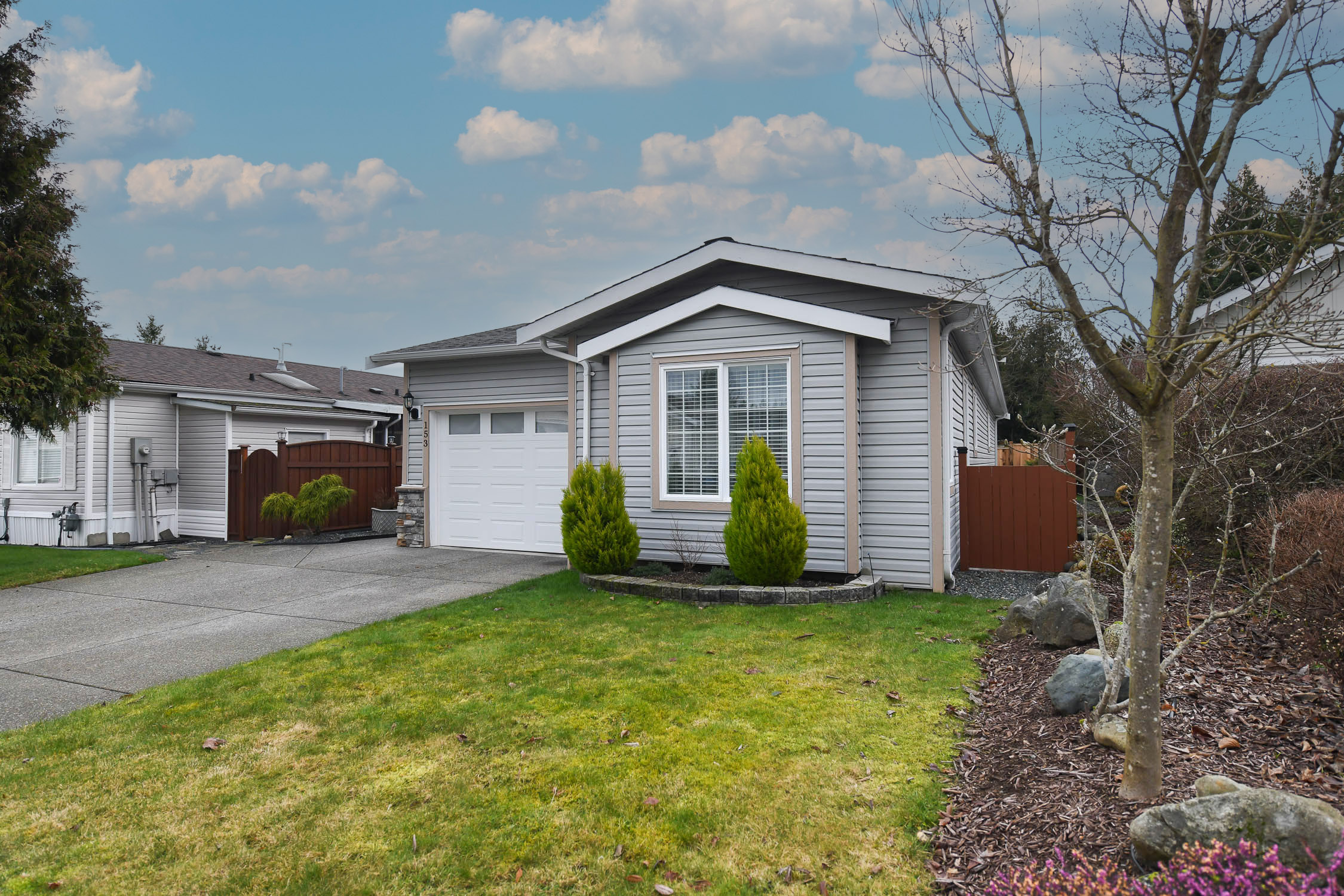 exterior view of 153 4714 muir rd courtenay bc showing 2013 built modular home with attached garage fenced yard and covered patio