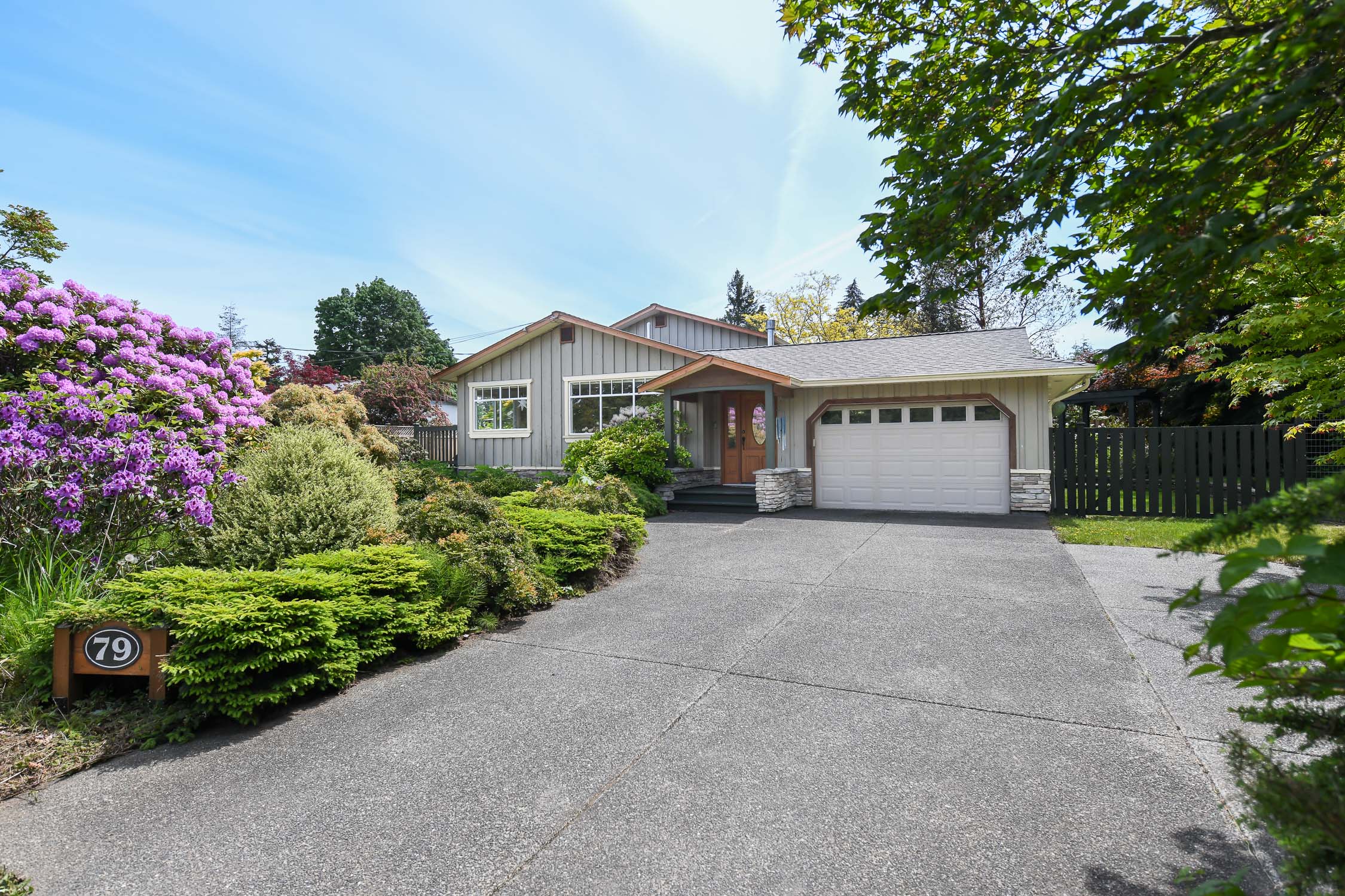 Front exterior view of 79 McGimpsey Rd in Campbell River, BC, showcasing a beautifully maintained home on a private, park-like 0.33-acre property with mature landscaping, detached workshop, and coastal surroundings&mdash;highlighting sought-after Vancouver Island real estate near the ocean, walking trails, and Storey Creek Golf Club.