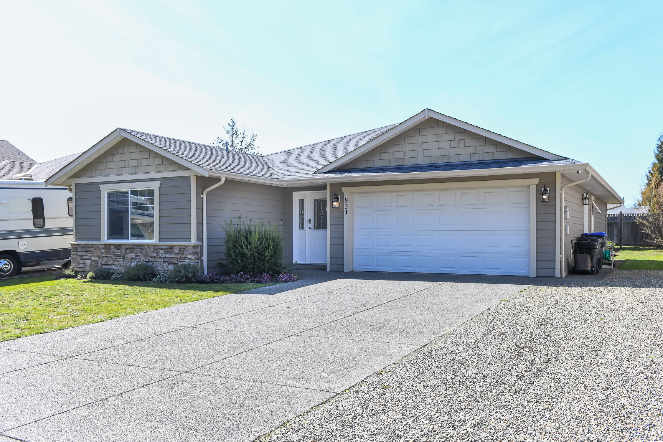 front exterior of 831 aspen rd comox bc showing modern rancher with double garage and fully fenced yard