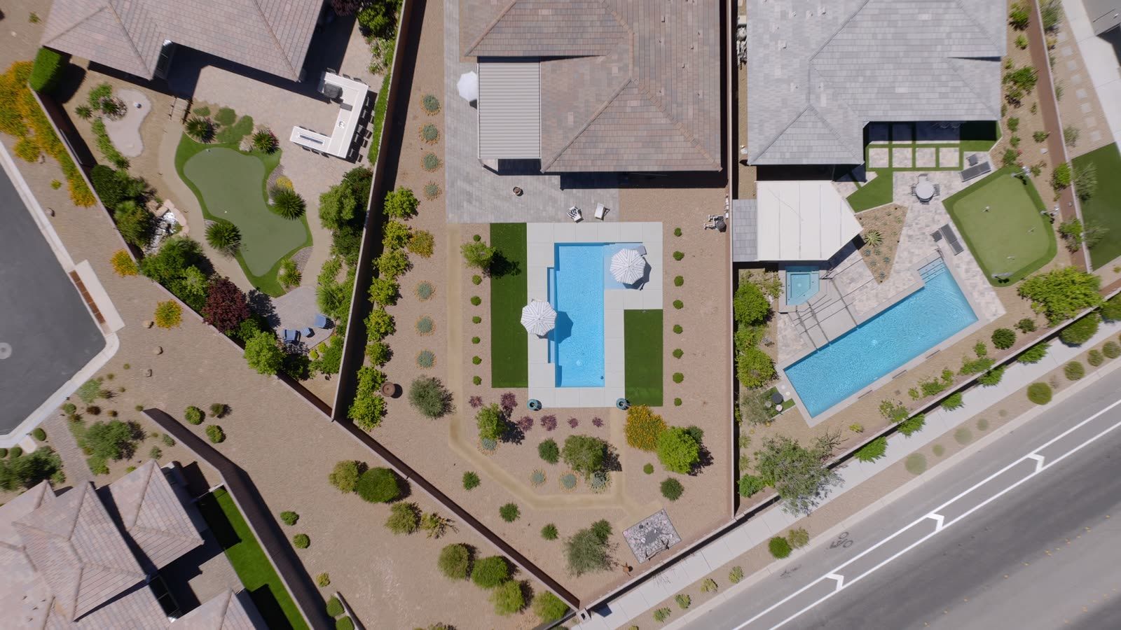Aerial view of desert-landscaped backyards with swimming pools and putting greens