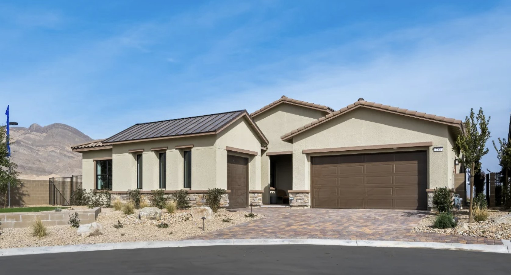 Single-story home with a two-car garage and paver driveway at Ashland by Taylor Morrison, mountains in the background