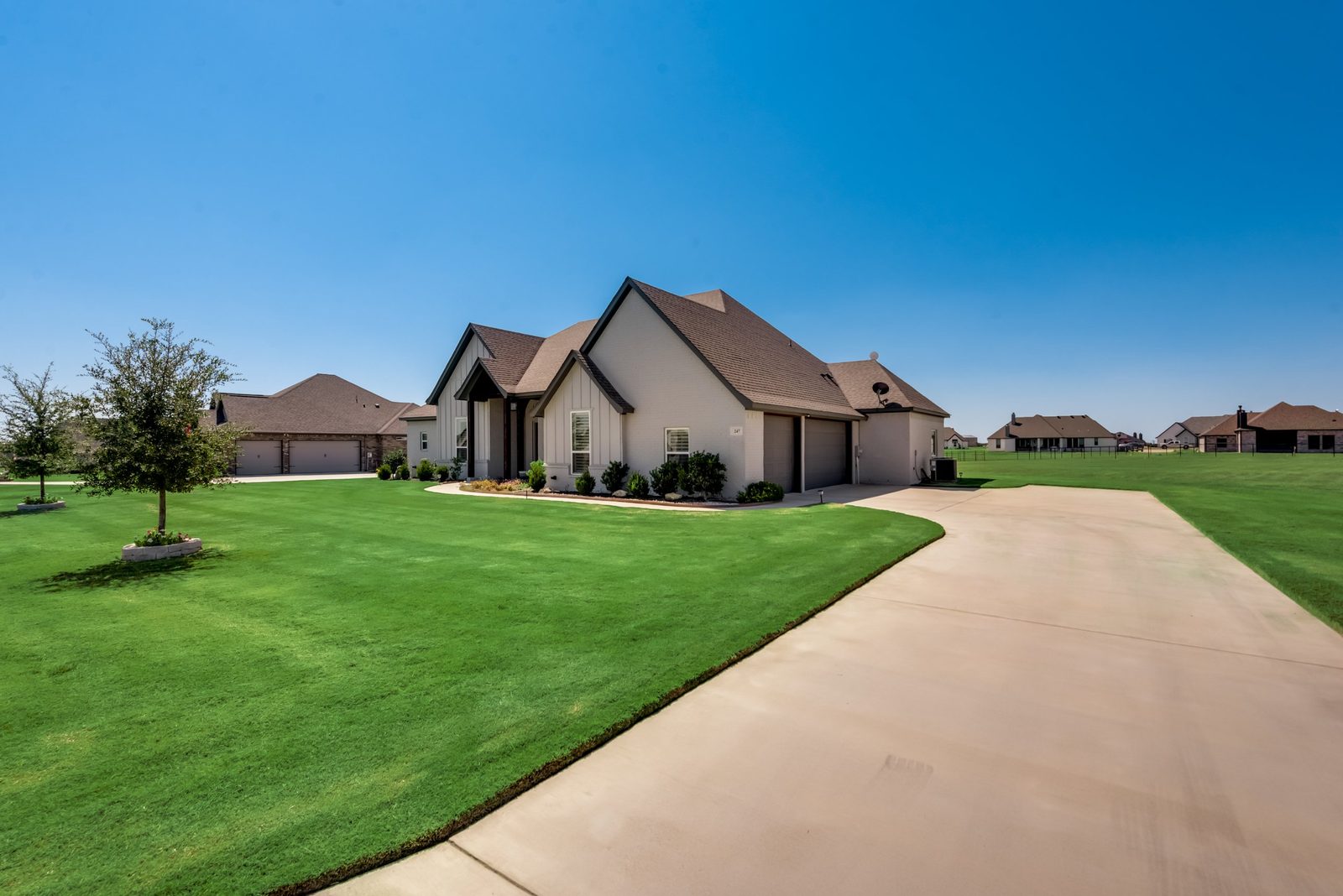 Single-story home with a long driveway and wide green lawn on an acreage lot in Dallas-Fort Worth